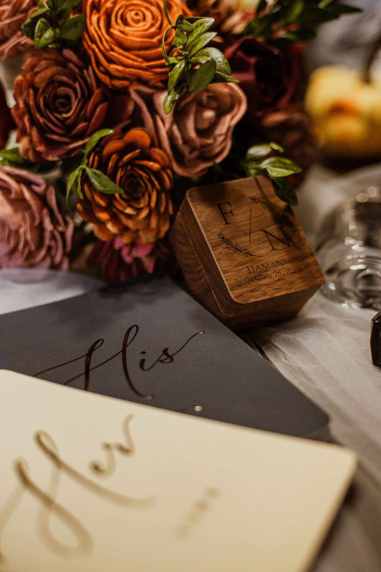 Close-up of autumn-colored roses with calligraphy wedding signage.