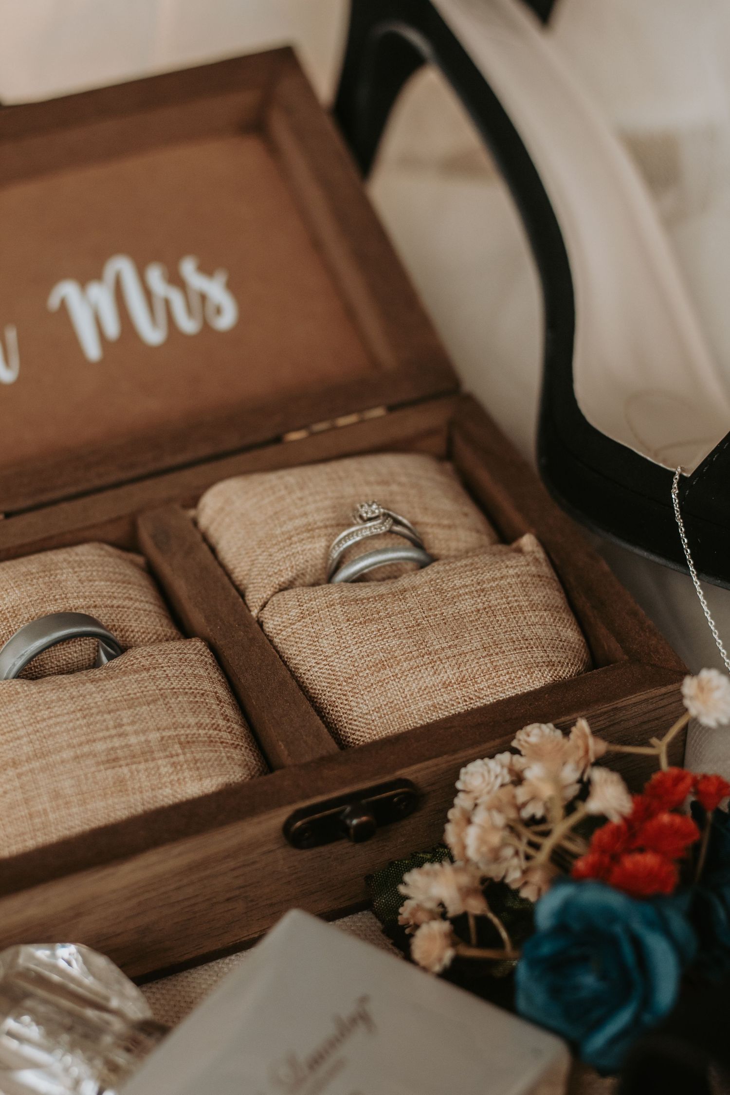 Wedding rings displayed in rustic wooden box with burlap lining.