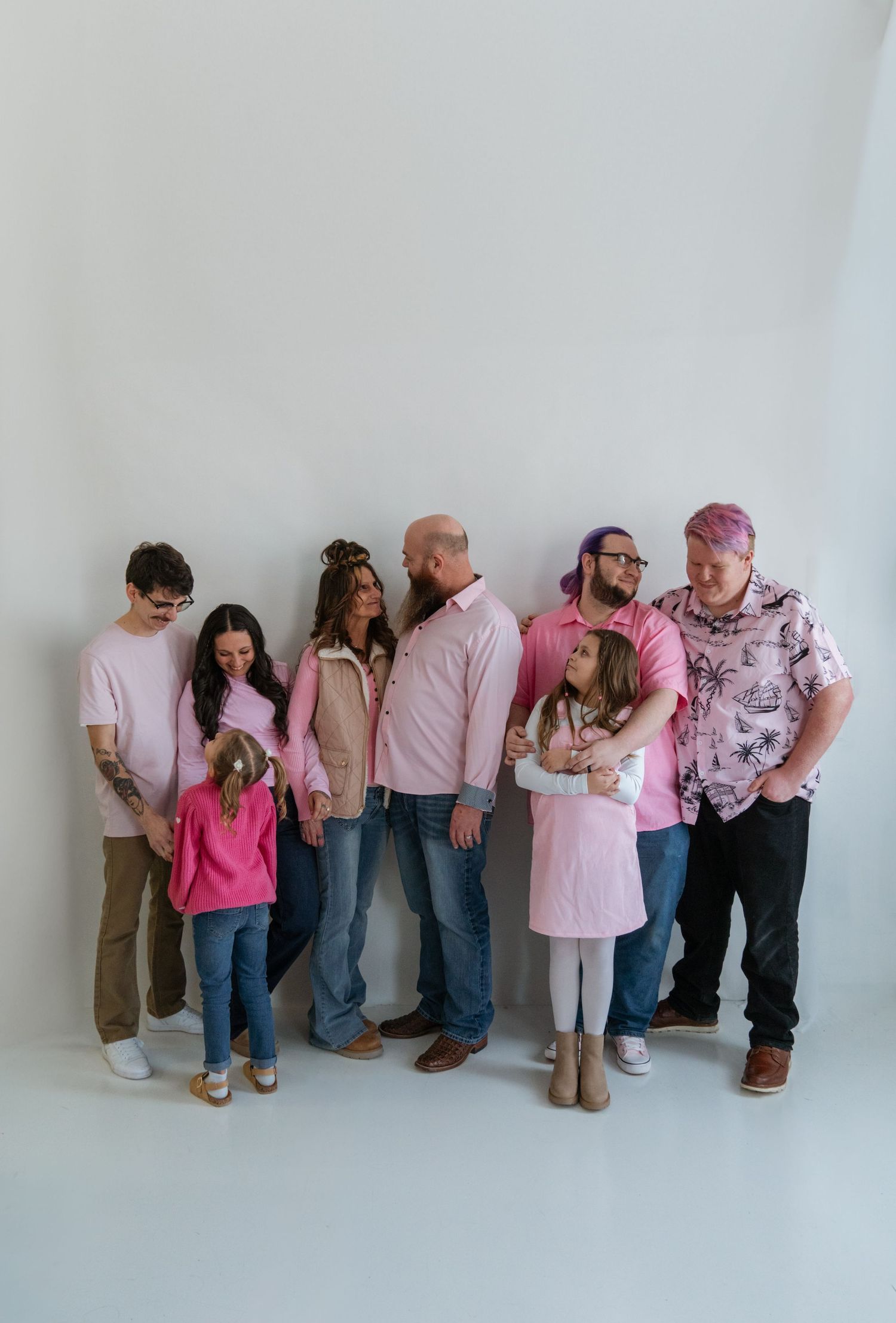 Group photo of people lined up against a white wall wearing pink and neutral tones.
