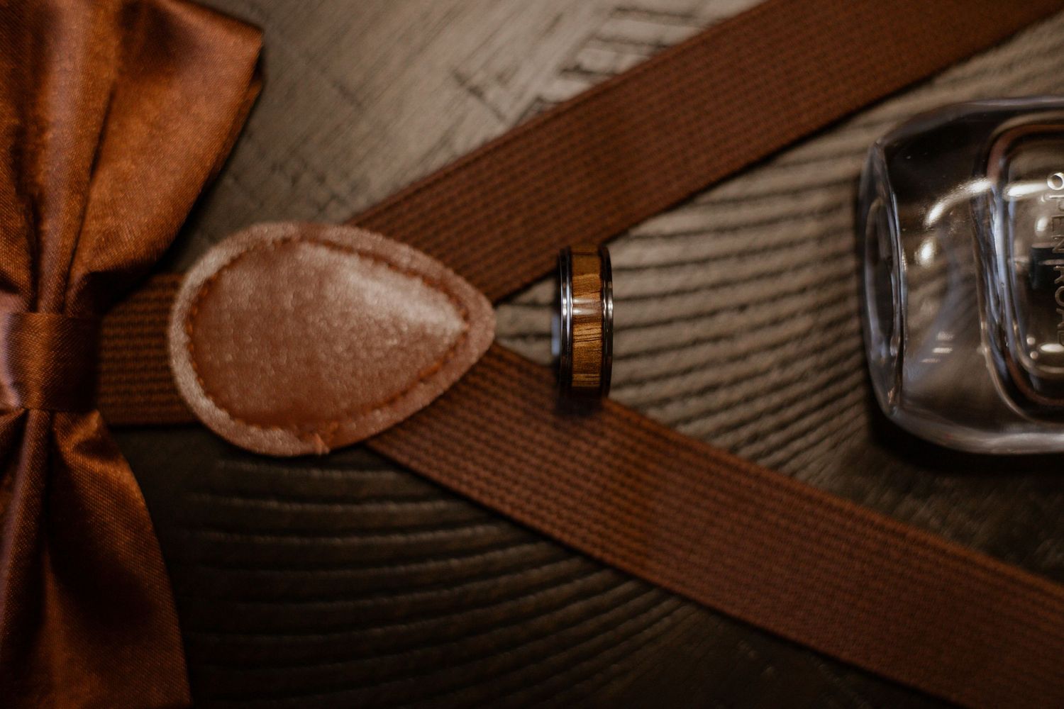 Wedding accessories and details arranged on brown textured surface.