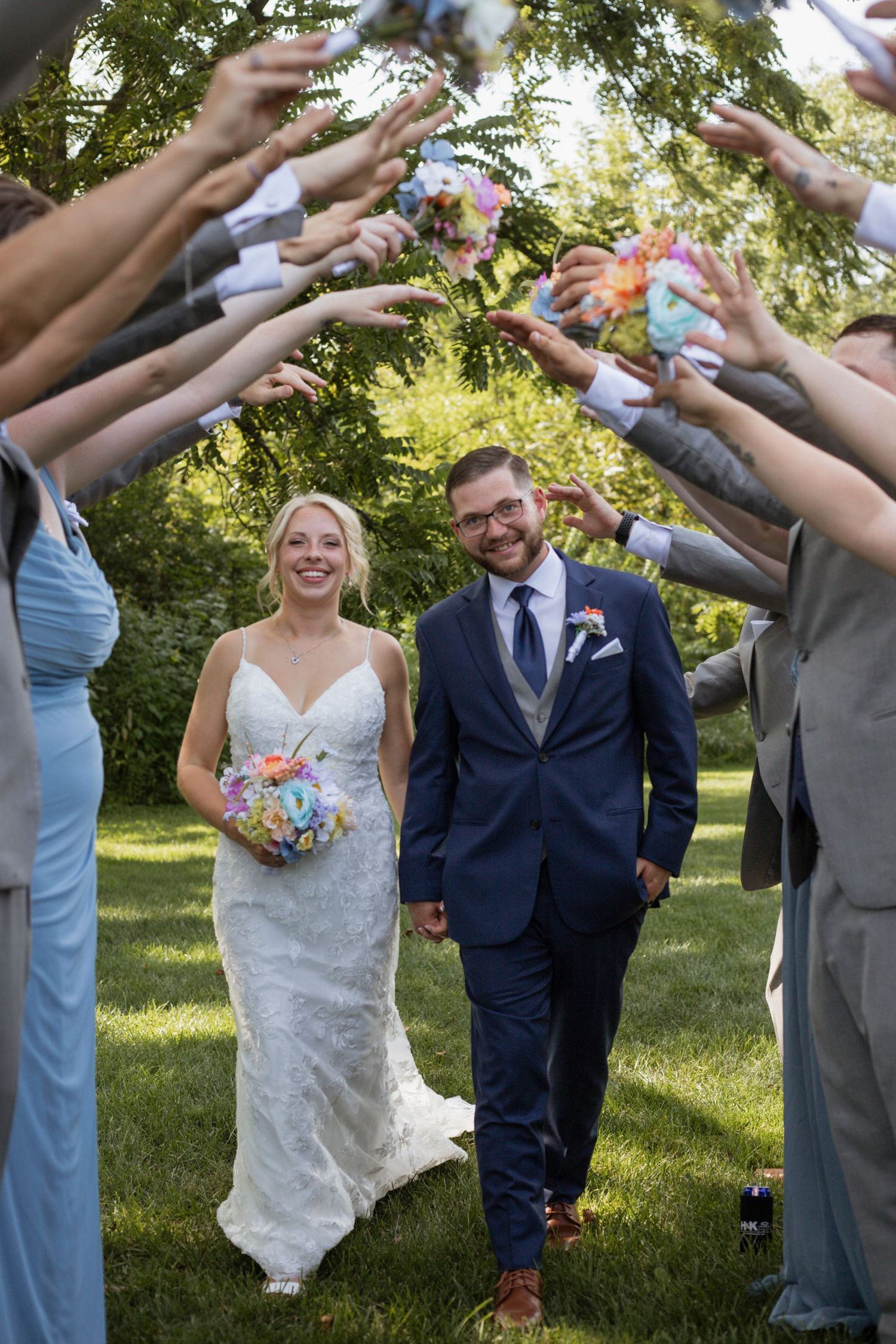 Wedding party forming a celebratory tunnel outdoors on a sunny day.
