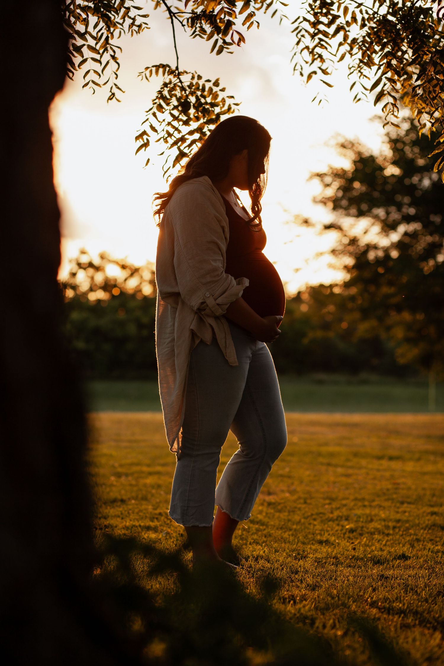 Silhouetted couple embracing in a field during golden sunset.