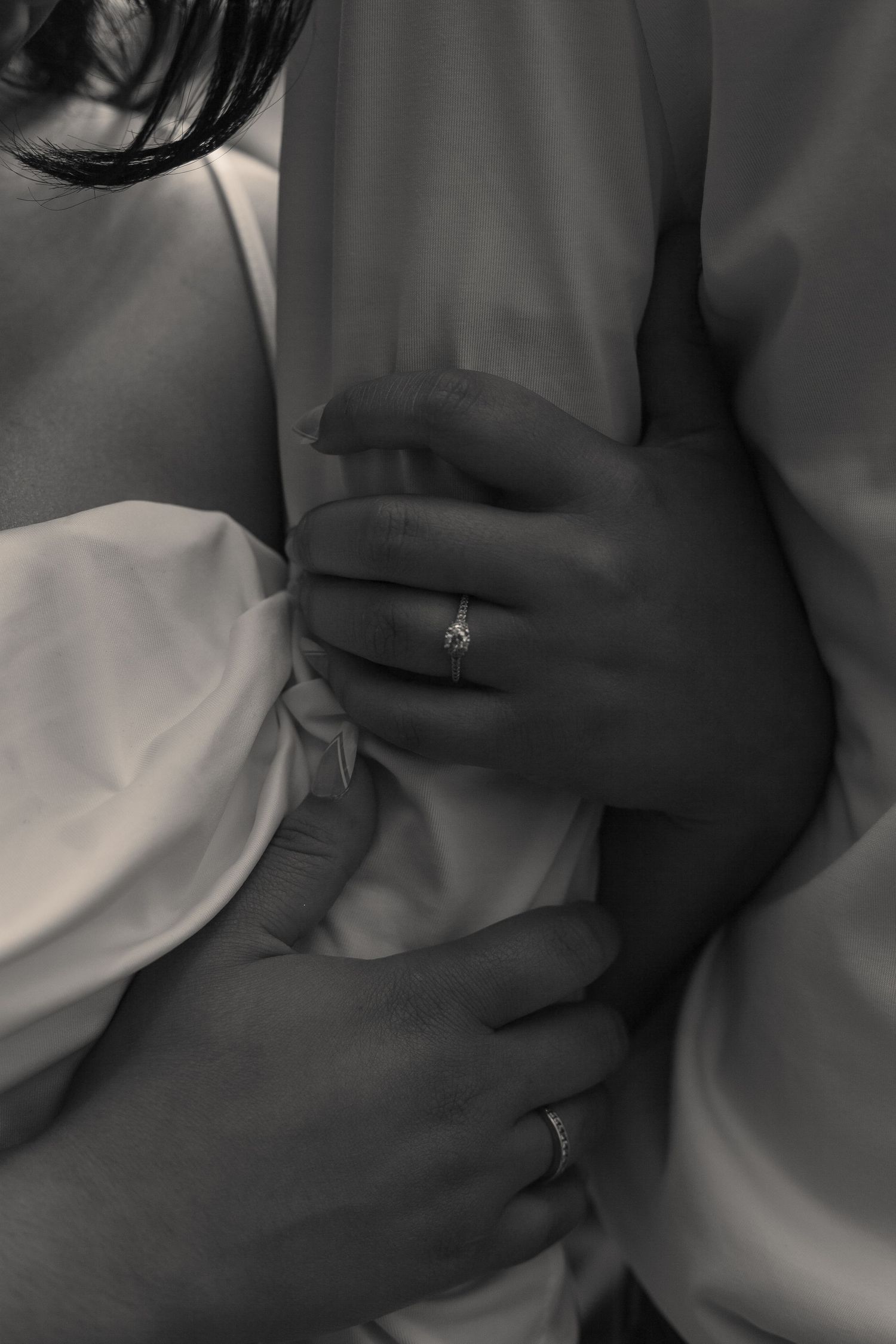 Close-up series of hands with engagement ring against fabric in monochrome.