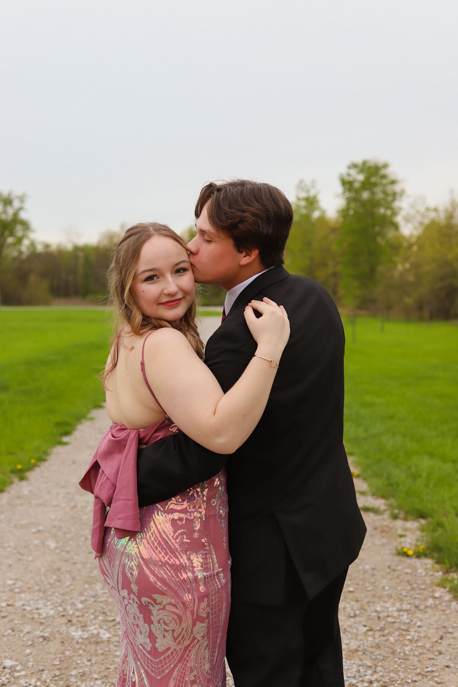 Couple sharing romantic moment on gravel path in spring field.