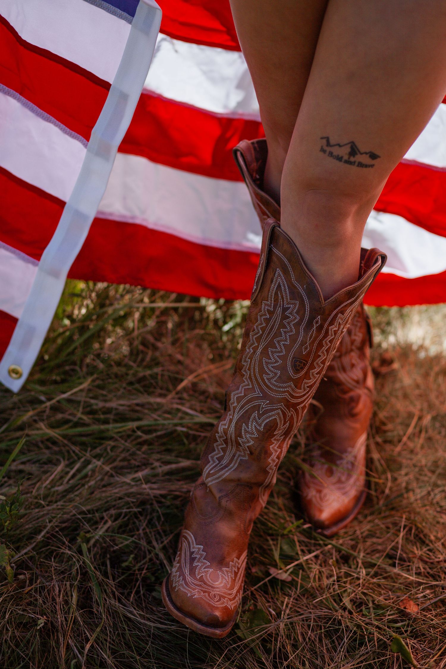 Close-up of brown leather cowboy boots with American flag in background.