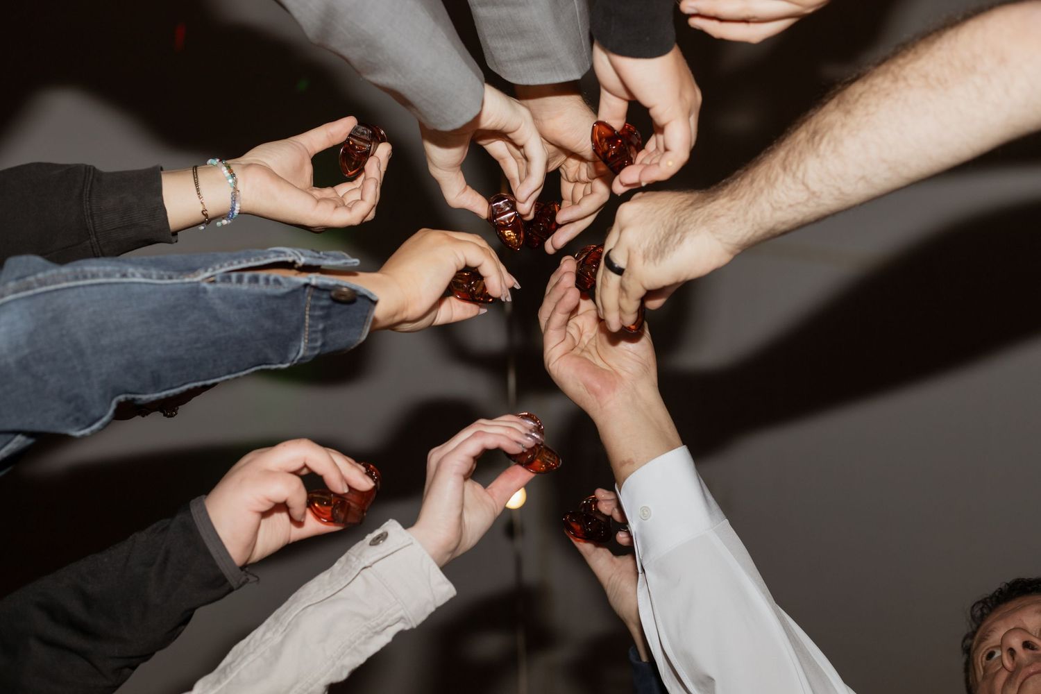 Hands reaching in to share shots during wedding celebration party.