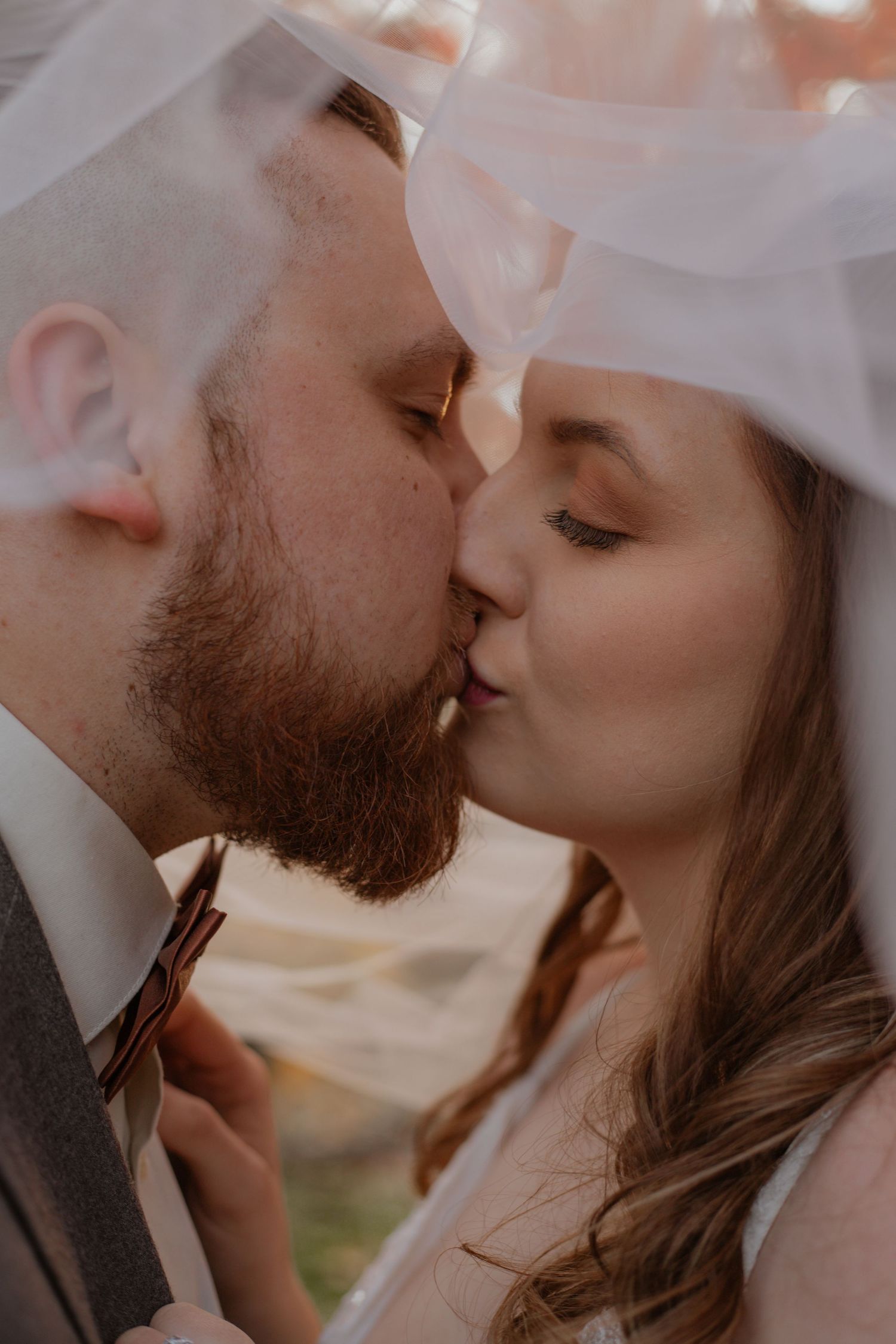 Intimate close-up wedding kiss captured in soft natural light.