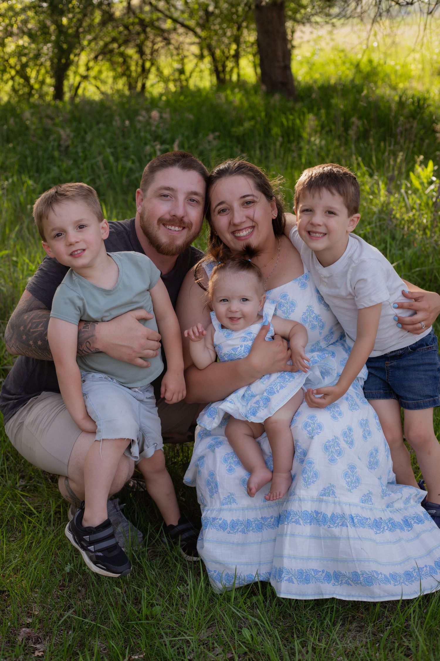 Happy family portrait series with everyone cuddled together on grass during golden hour.