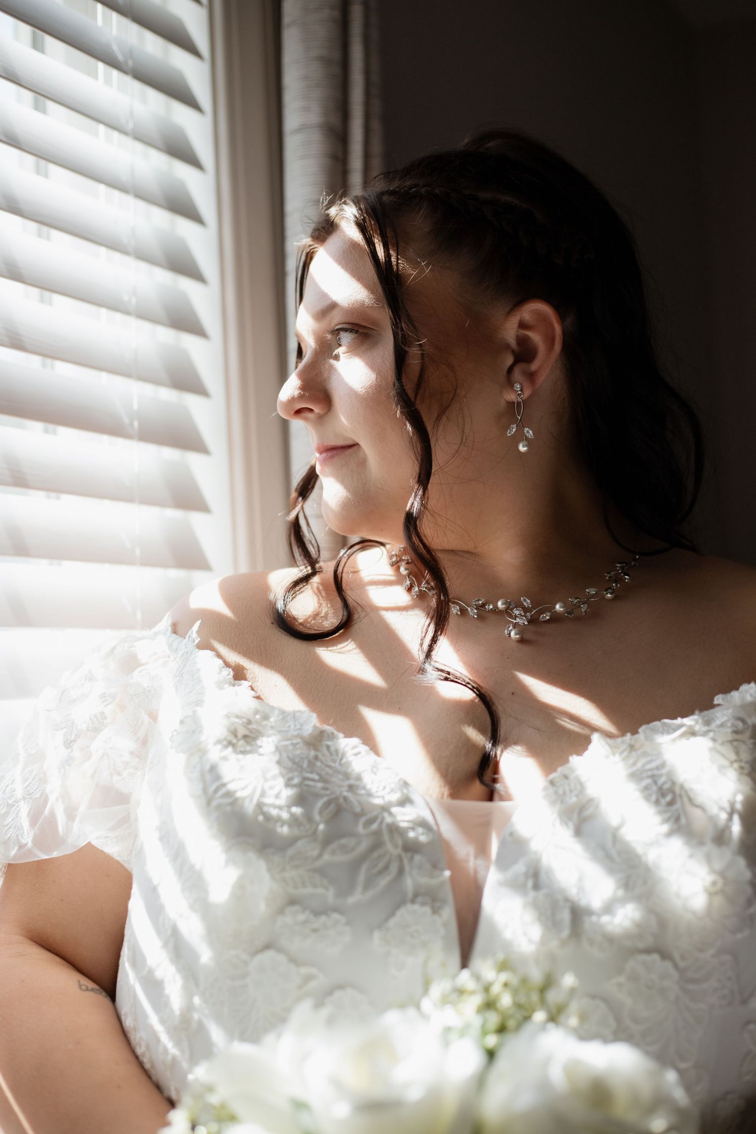 Dramatic window light portrait with white lace details and jewelry.