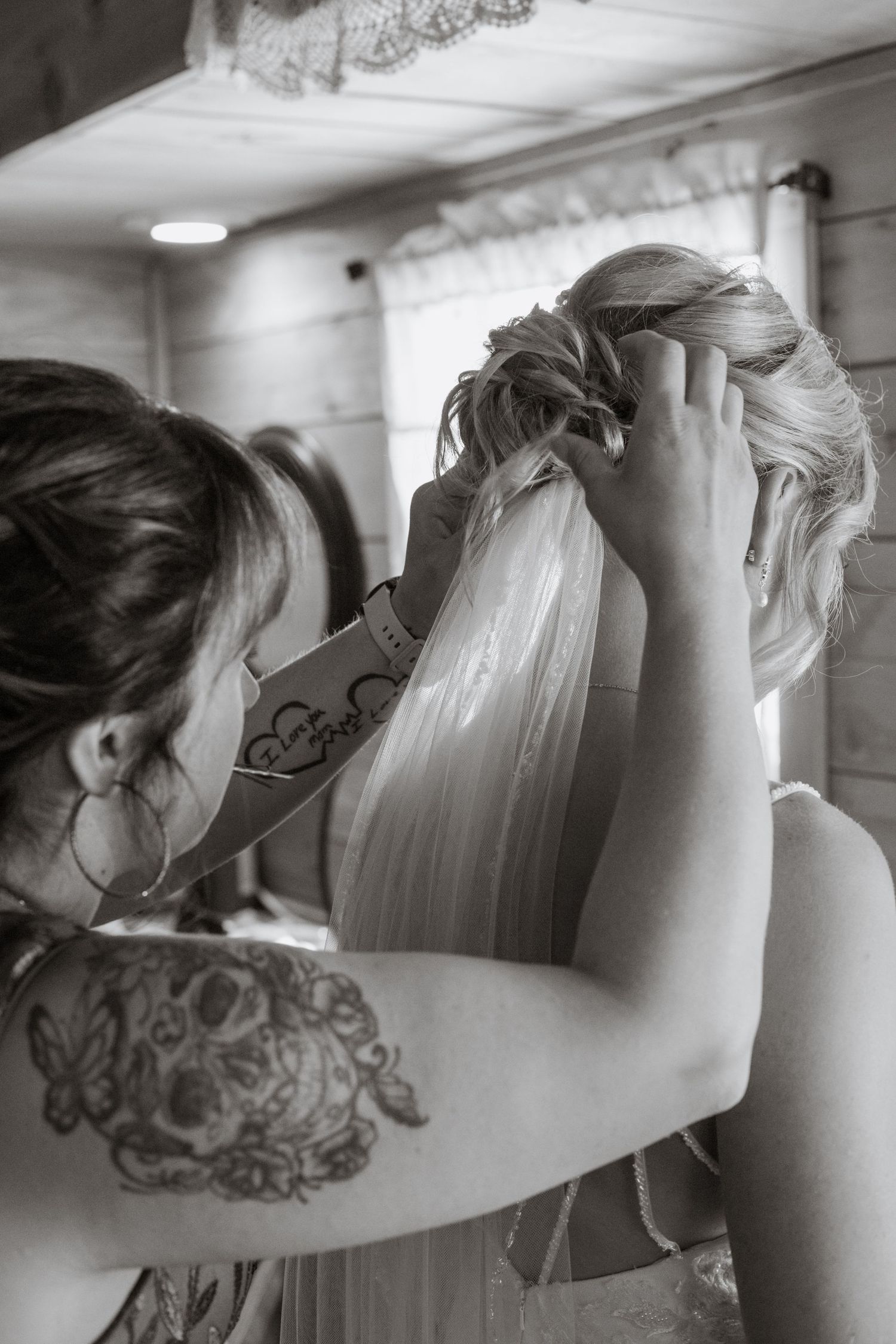 Black and white photo showing detailed preparation of a bridal veil and hairstyling.