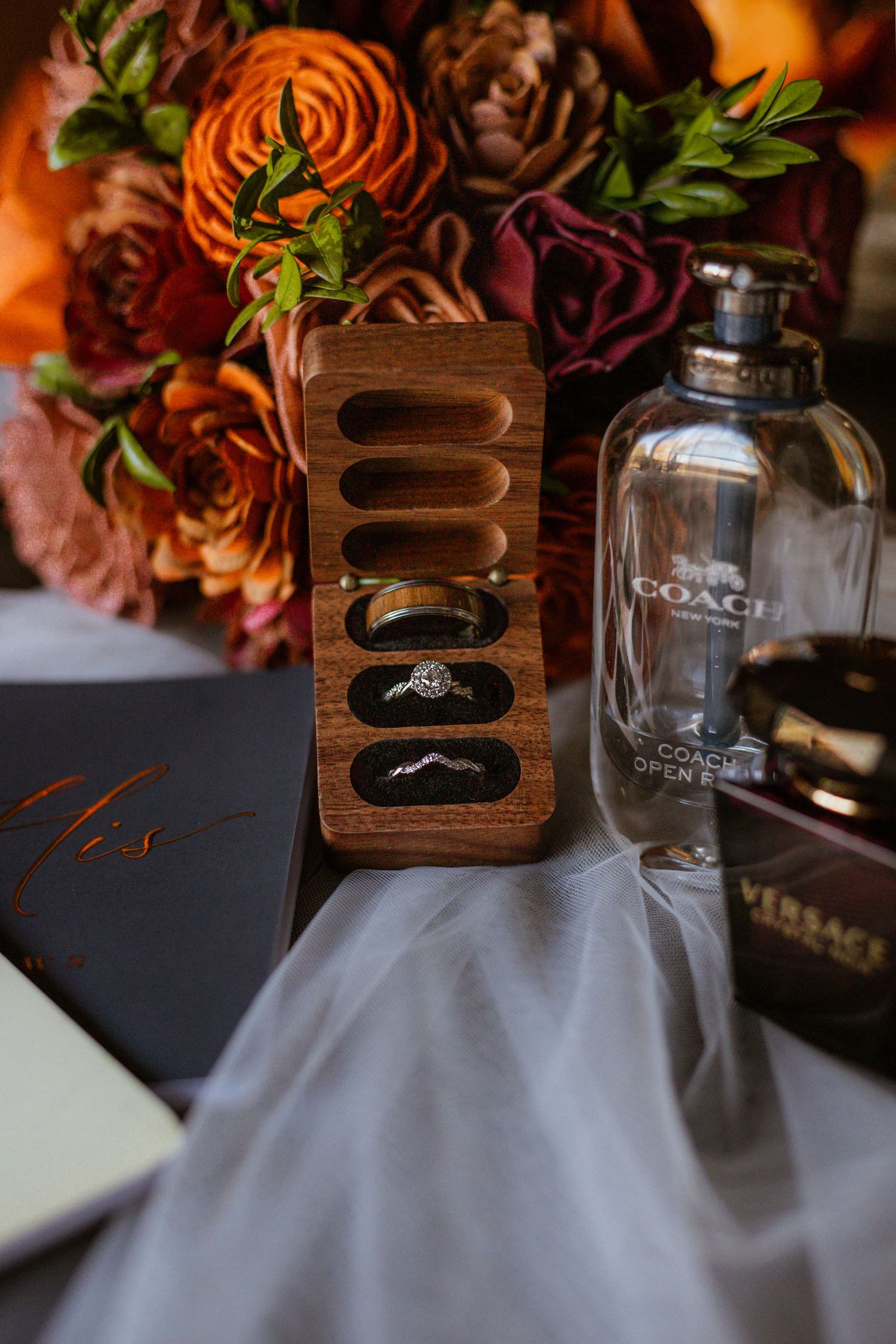 Wedding detail shot of orange roses and wooden ring box on table decor.