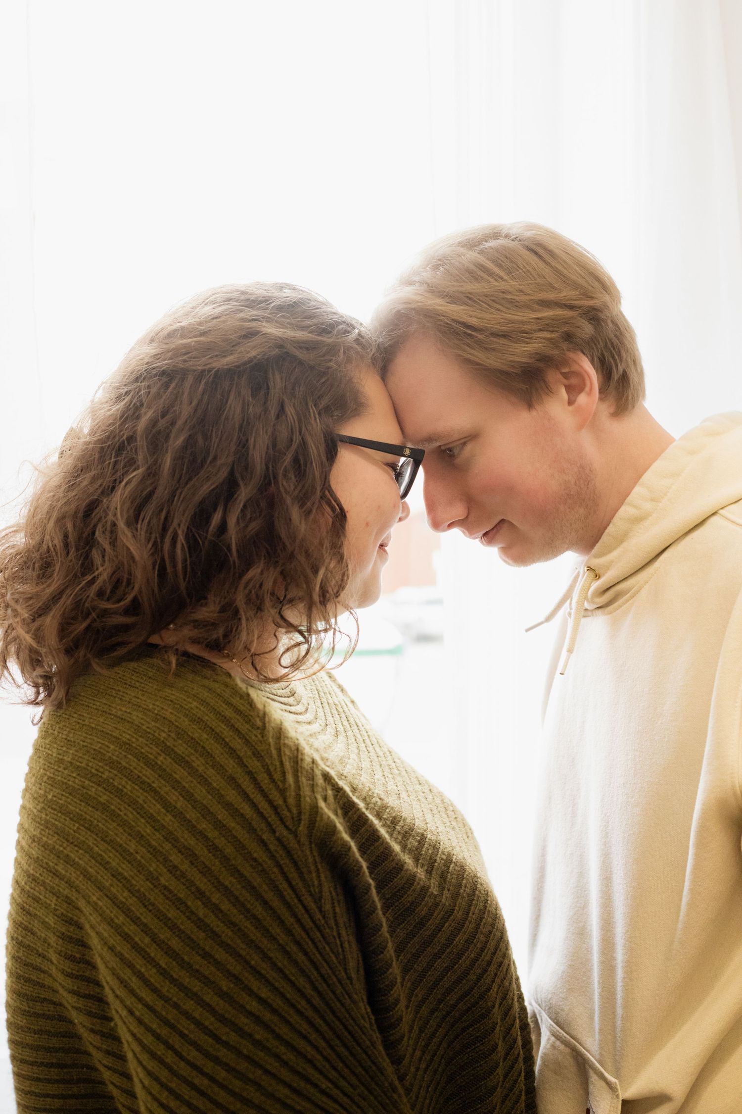 Intimate silhouette of couple in warm window light.