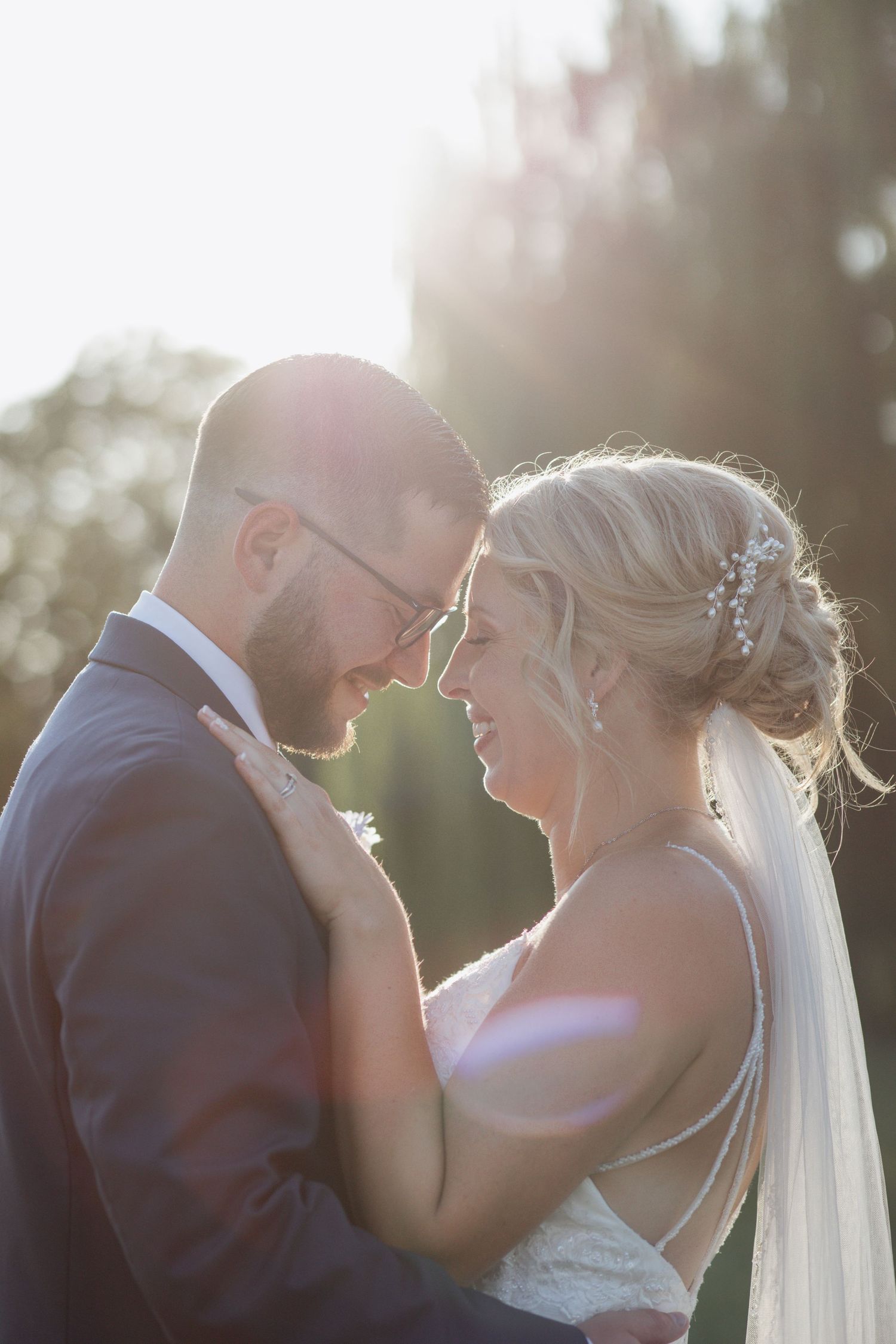 Romantic sunset wedding portraits with soft golden light and lens flares.
