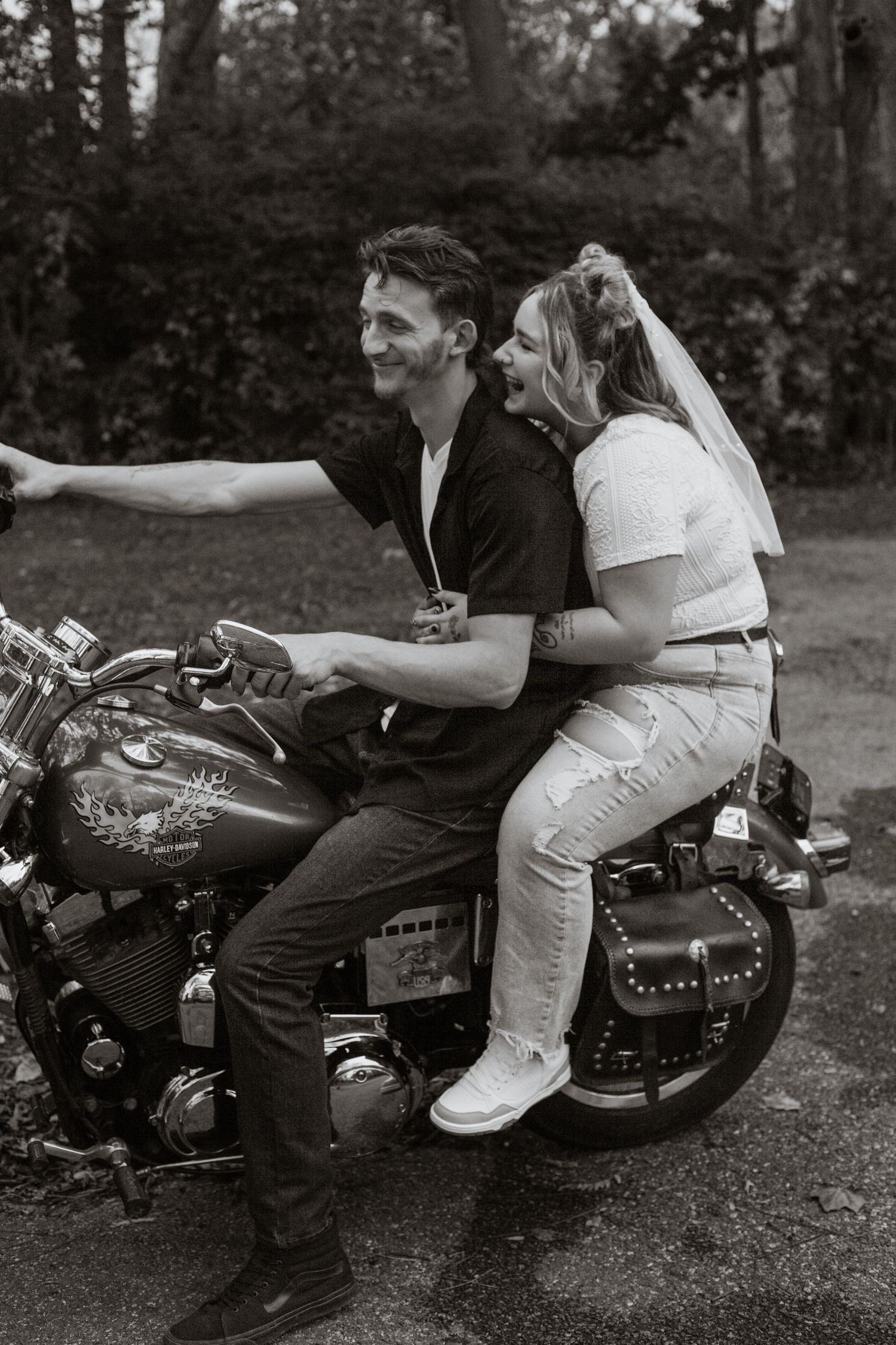 Couple sitting together on a motorcycle in a casual outdoor setting.