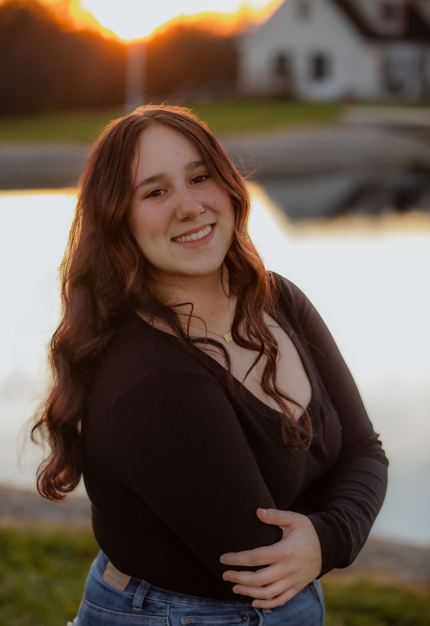 Portrait session at sunset with warm golden light reflecting off water in the background.
