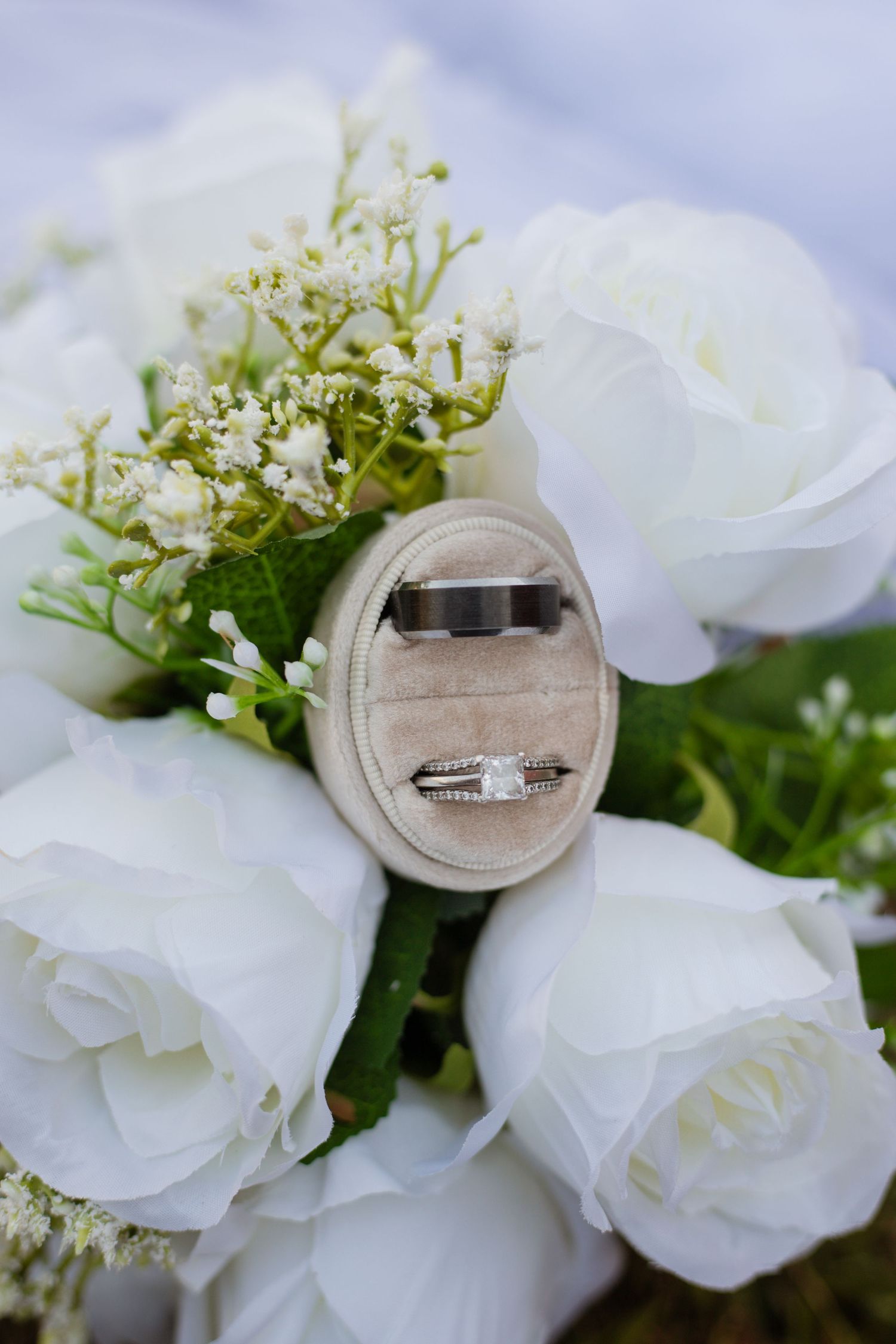 Diamond engagement ring and wedding band displayed with white roses and delicate baby's breath.