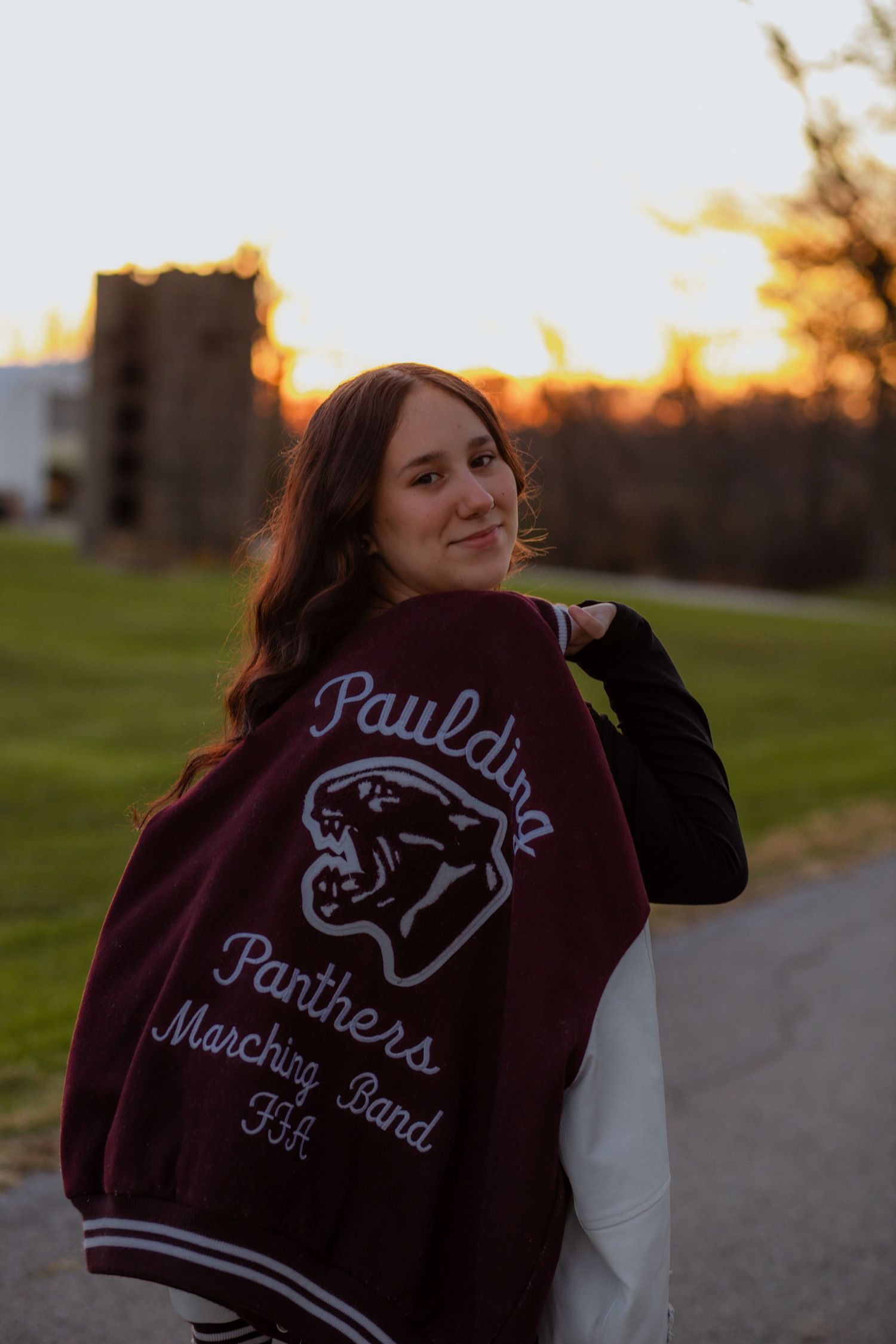 Sunset photos featuring a maroon band letterman jacket with embroidered details.