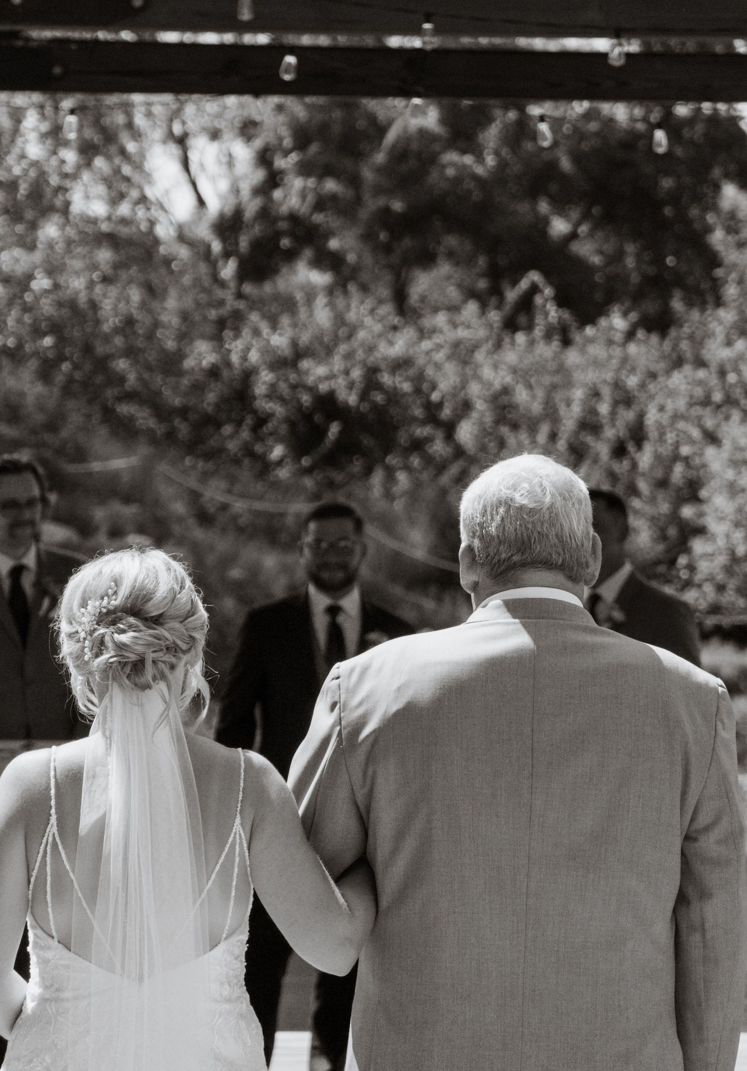 Black and white photo capturing a wedding ceremony processional moment.