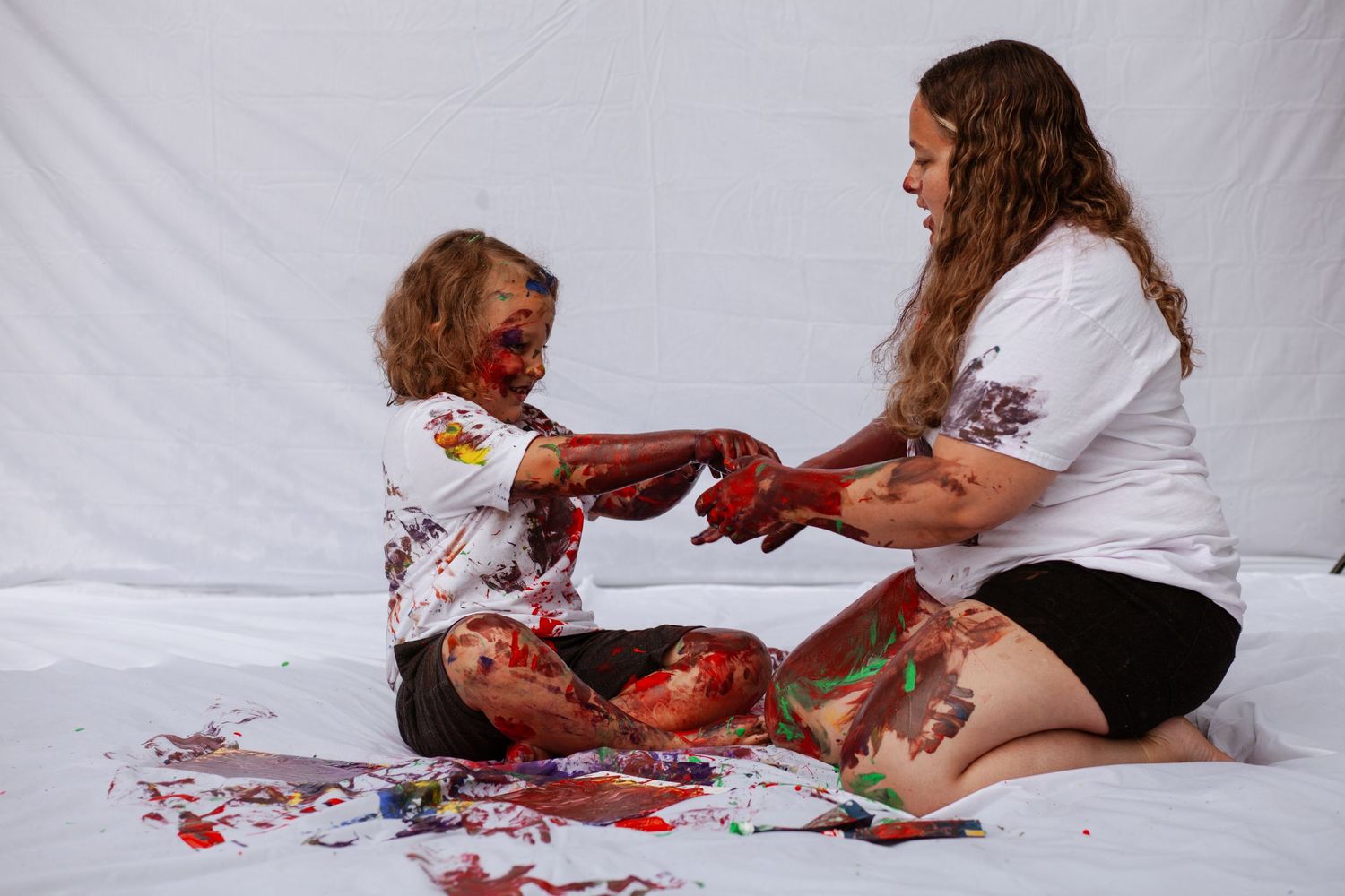 Creative paint session with people playing and making art on white surface.