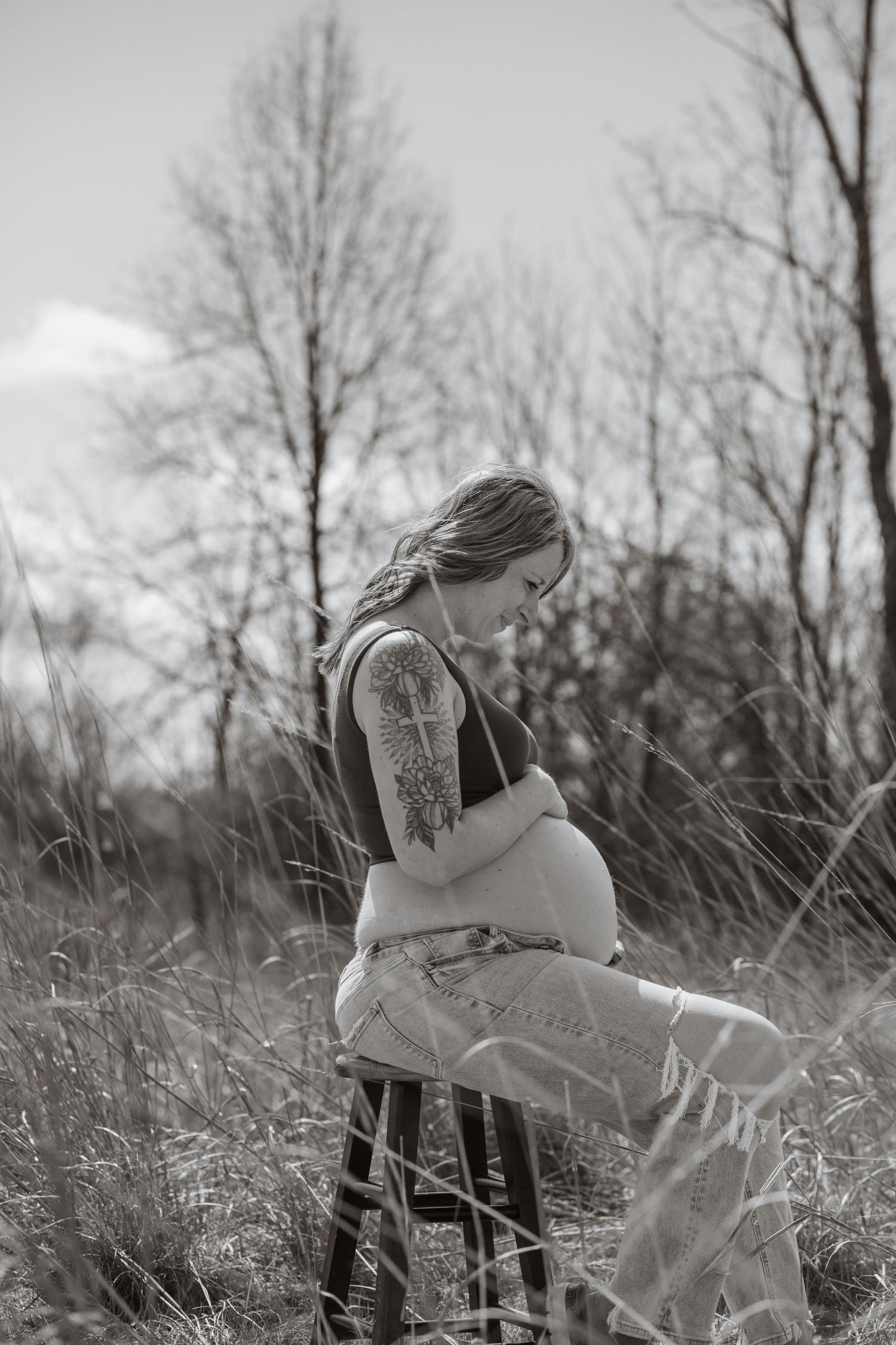 Black and white outdoor maternity photos captured in a natural field setting.