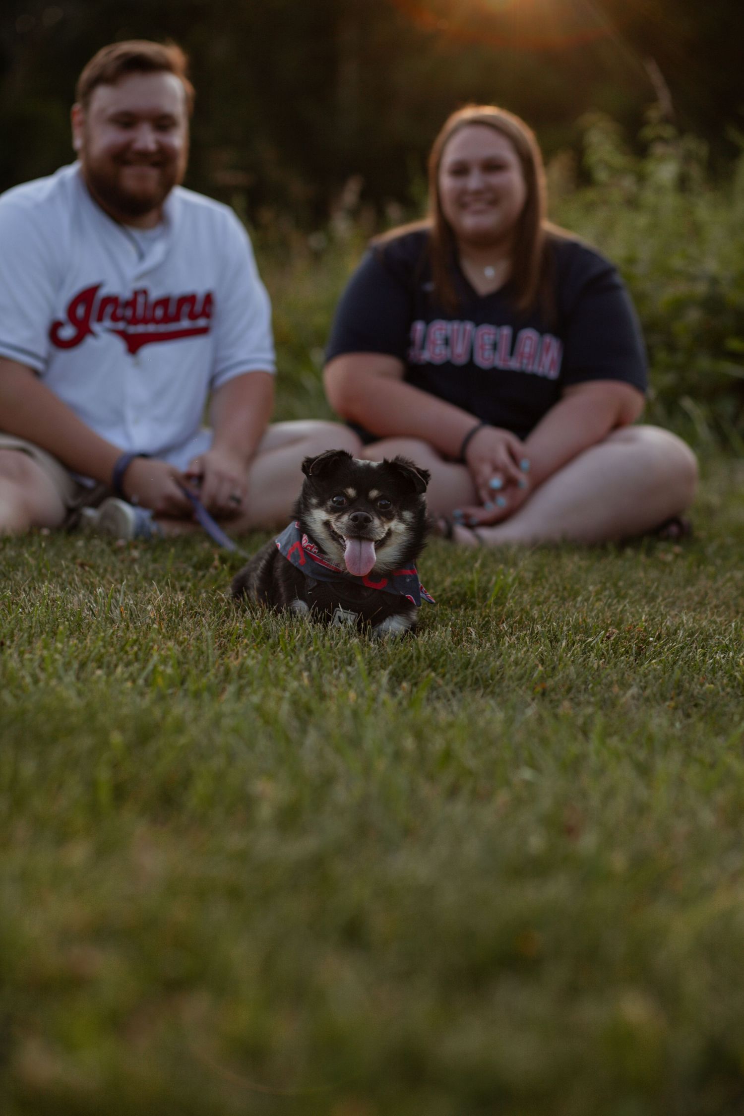 Couple relaxing on grass during golden hour outdoor photoshoot.