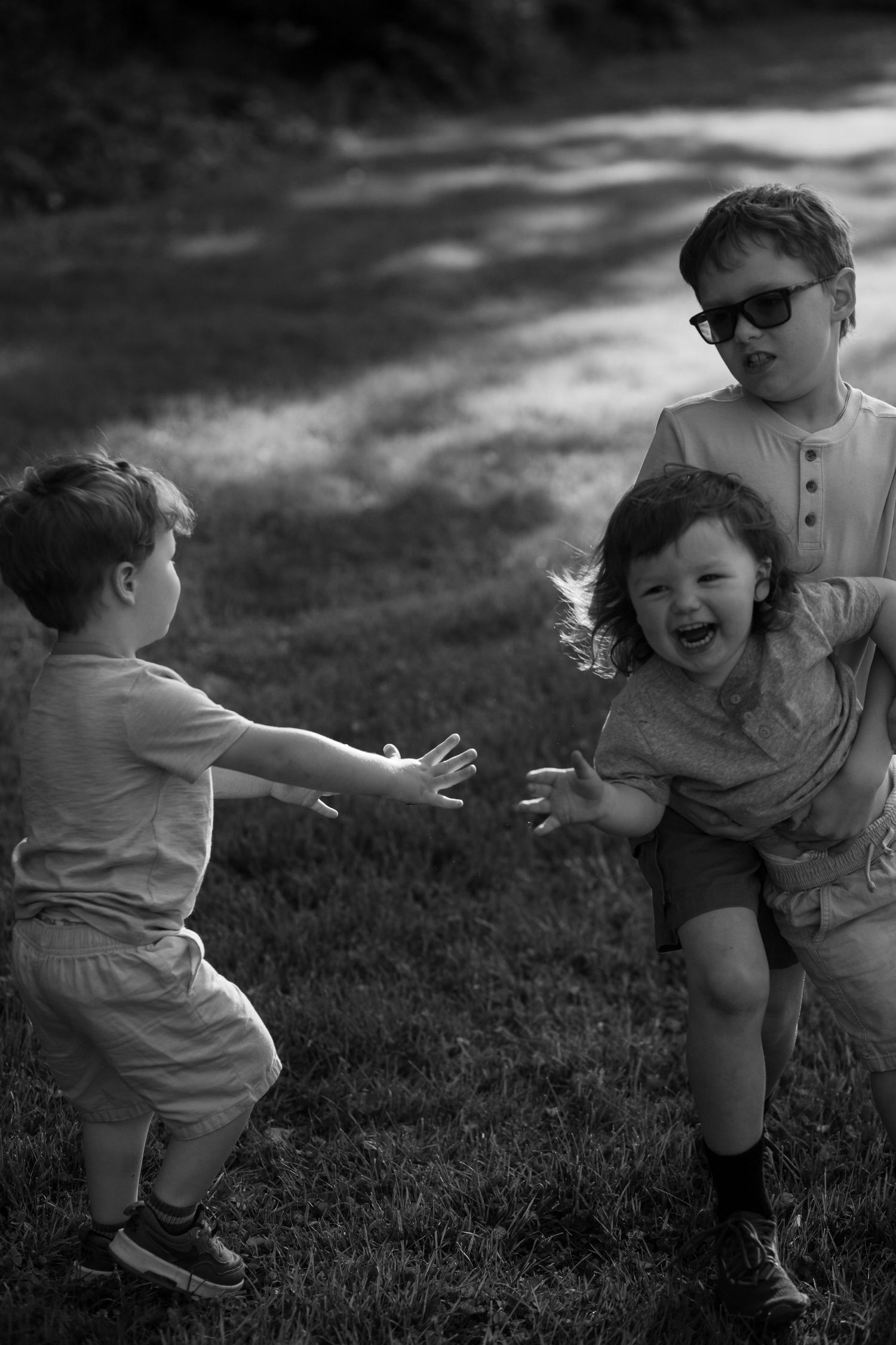 Black and white sequence of joyful outdoor play and laughter in a grassy area.
