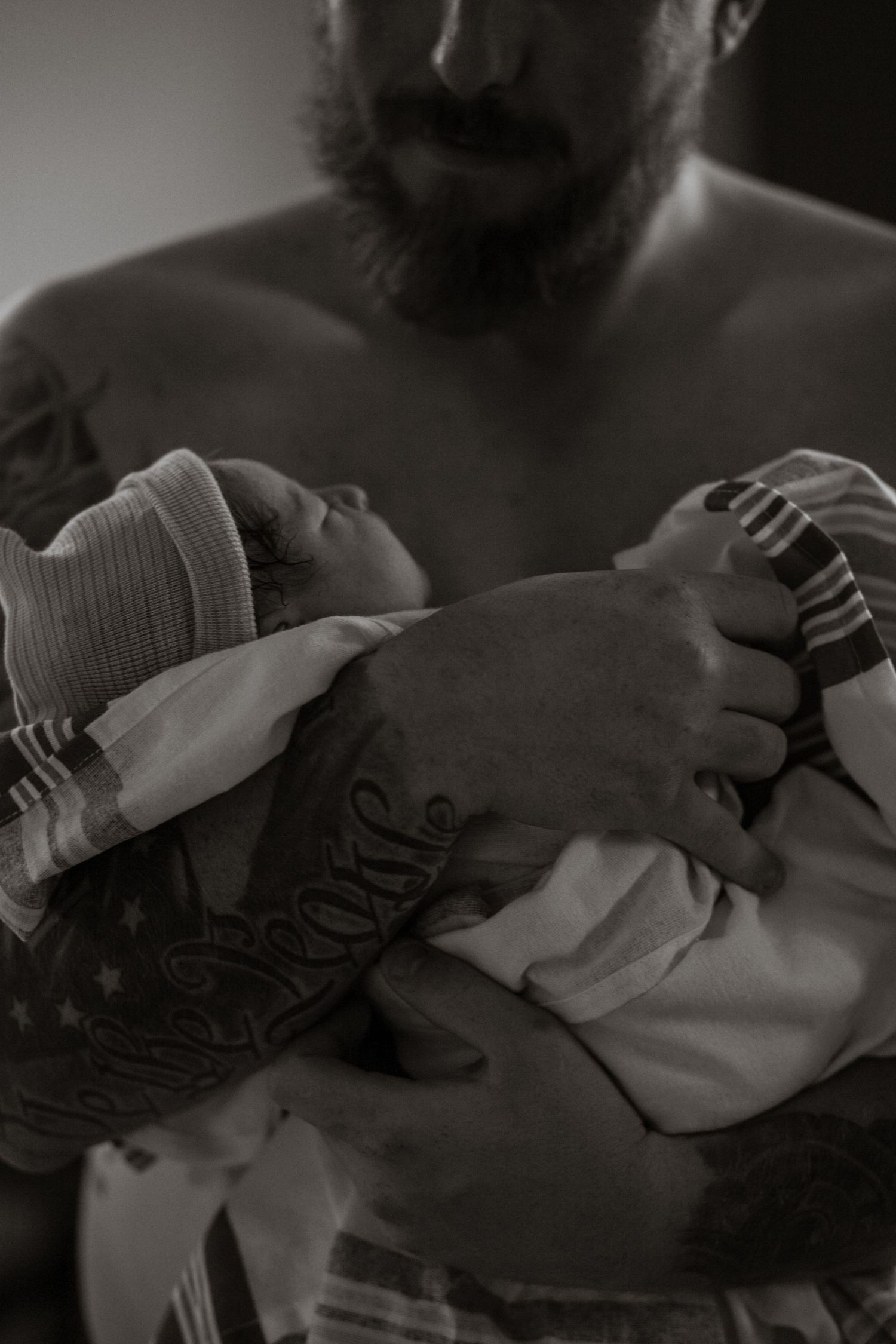Black and white intimate portrait of newborn baby being held.