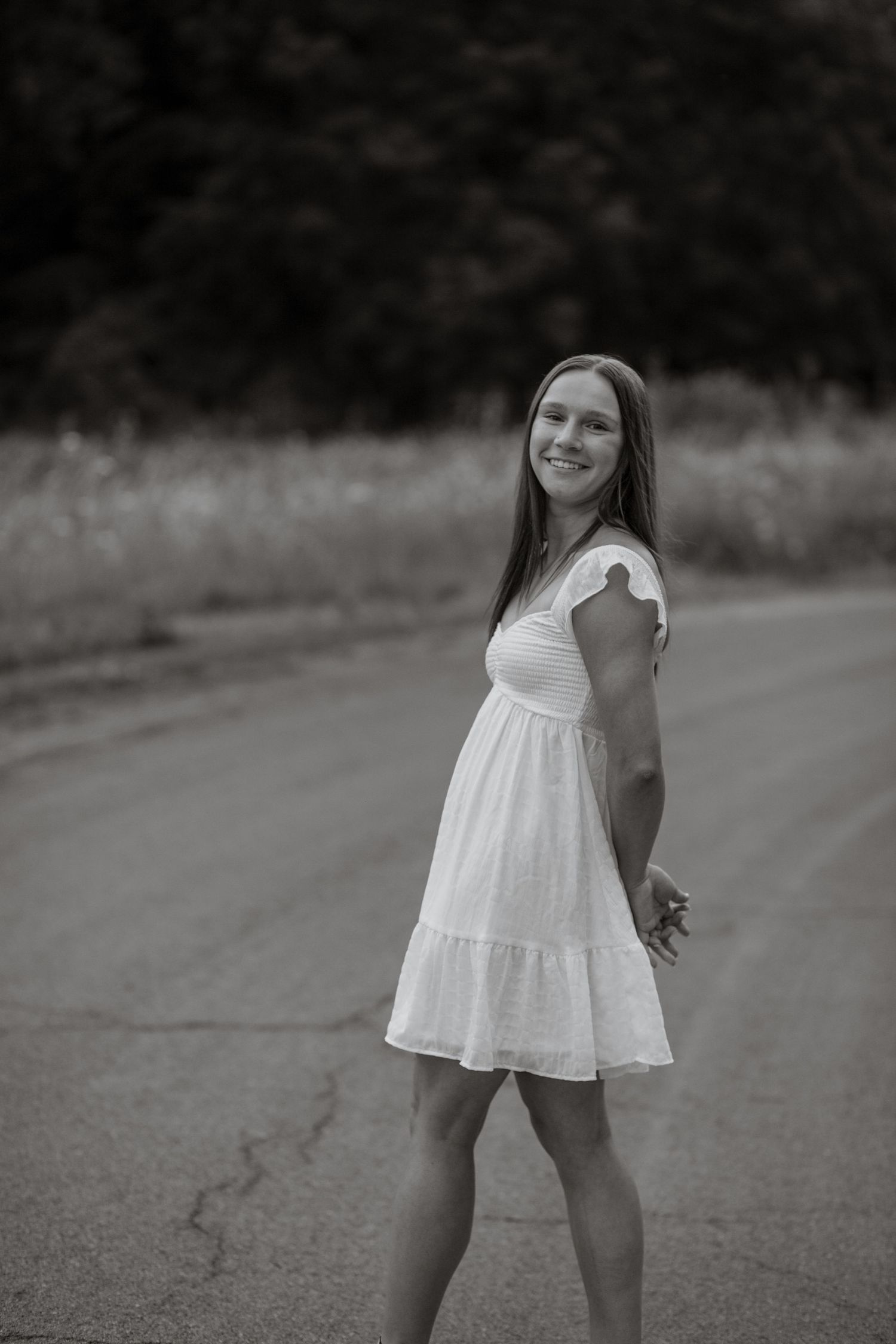 Black and white photo of flowing white dress on country road.