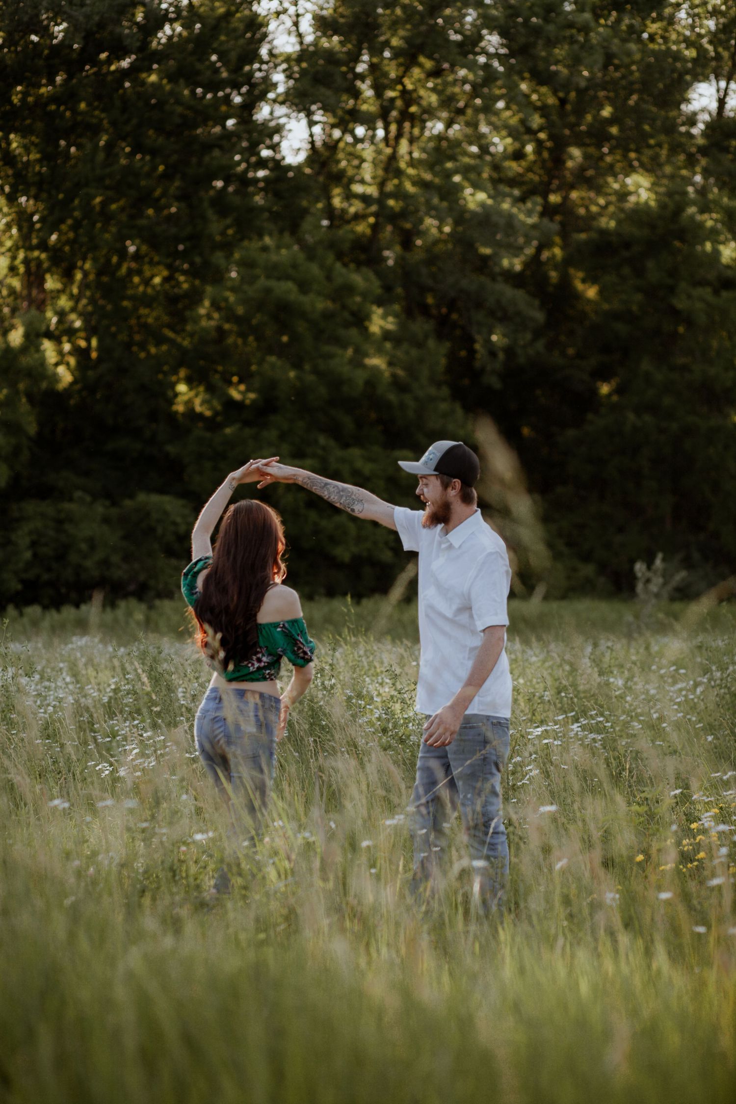Couple playing and dancing together in a summer meadow at golden hour.