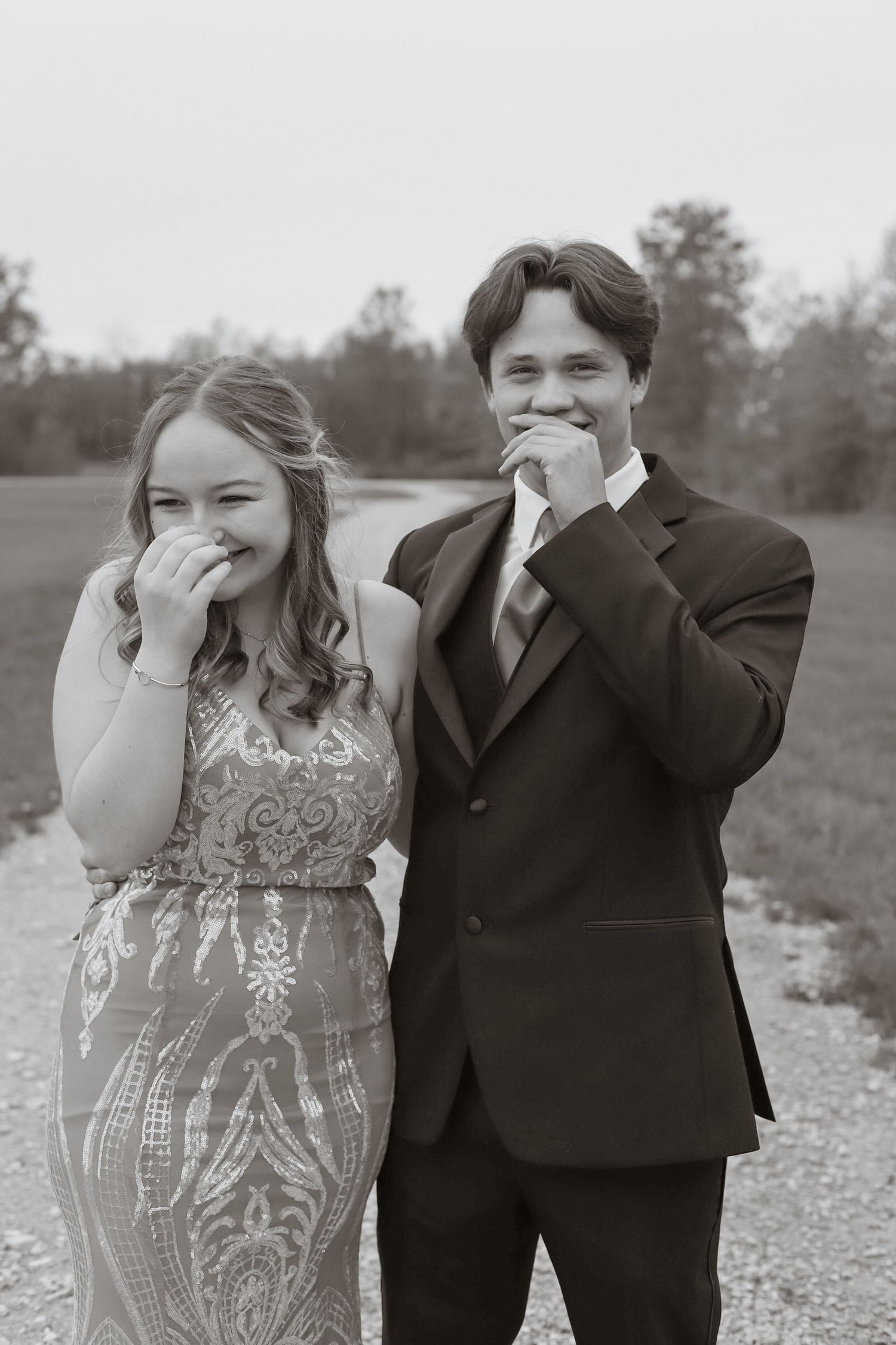 A couple in formal attire share a candid laughing moment together during a special occasion.