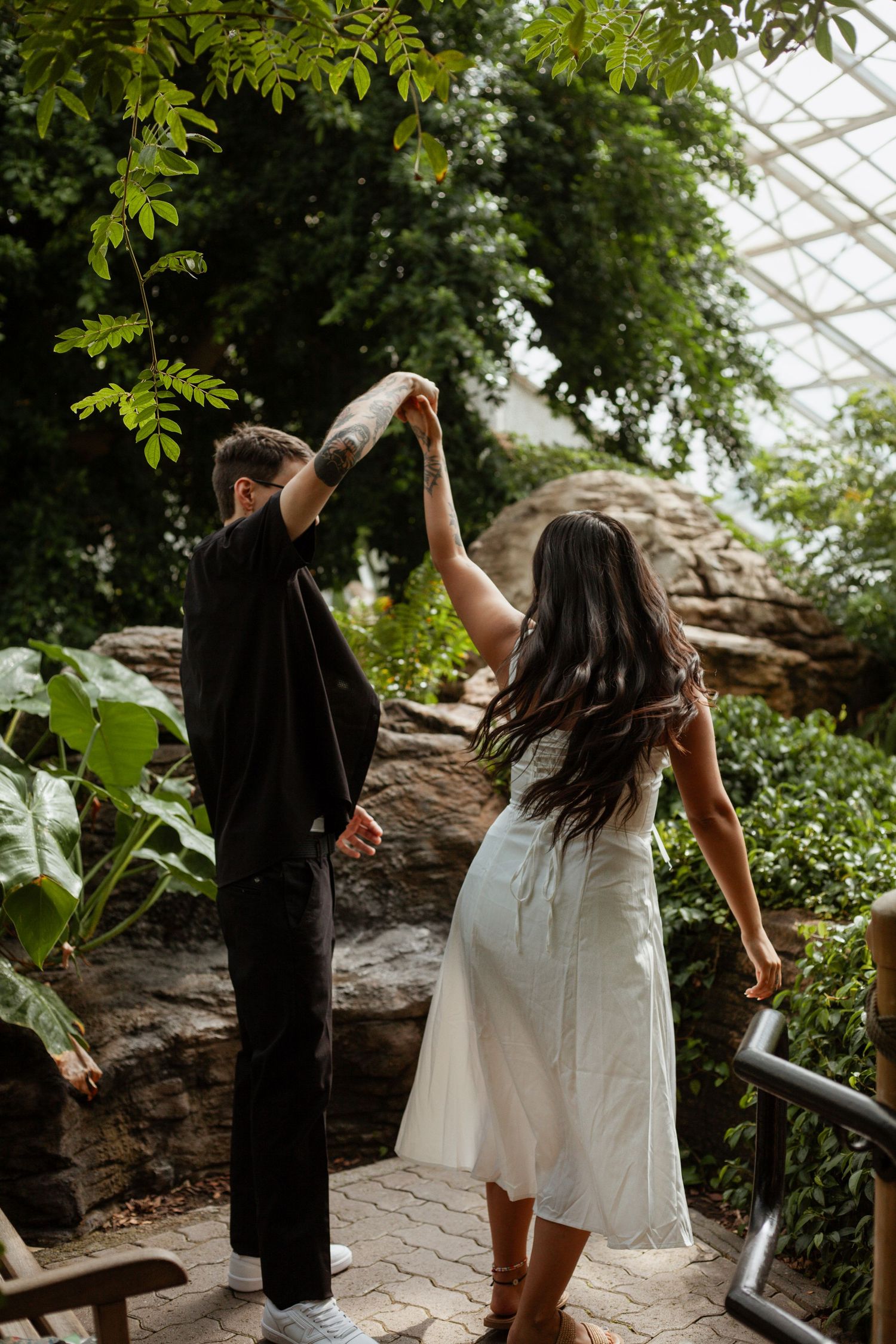 Dancing couple in a greenhouse surrounded by lush greenery.