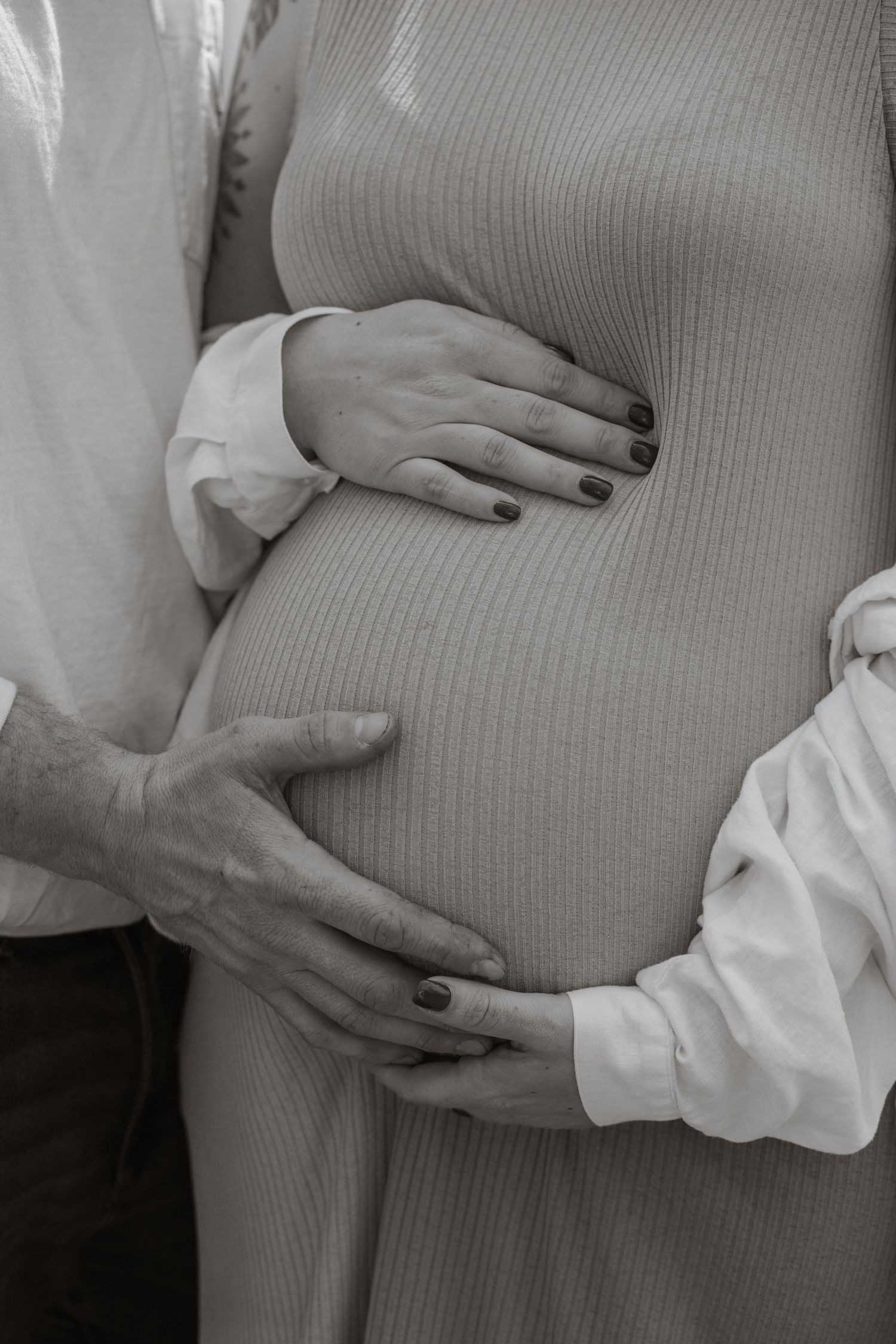 Close-up series of hands gently cradling a pregnant belly in a gray ribbed top.