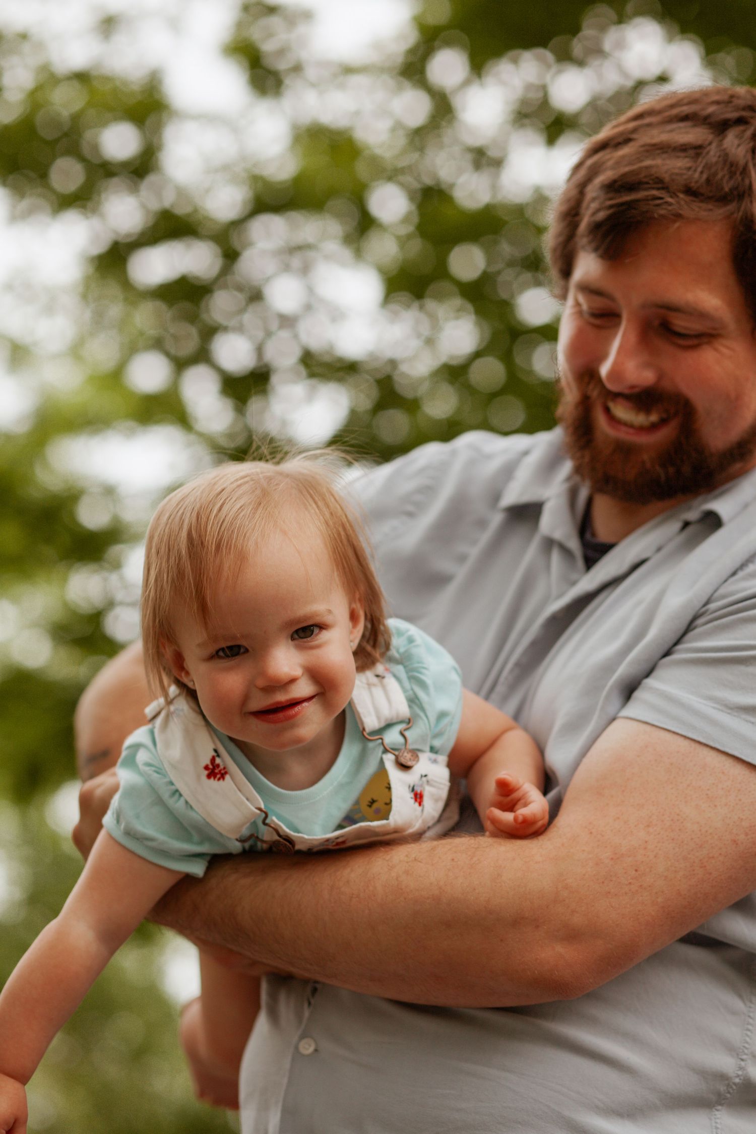 Playful sequence of a toddler being lifted and swung in the air outdoors.