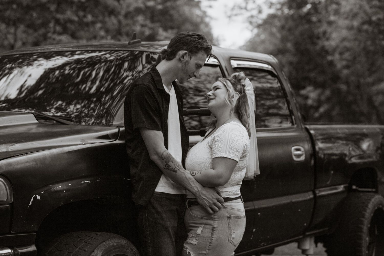 Romantic moment captured against a parked car in evening light.