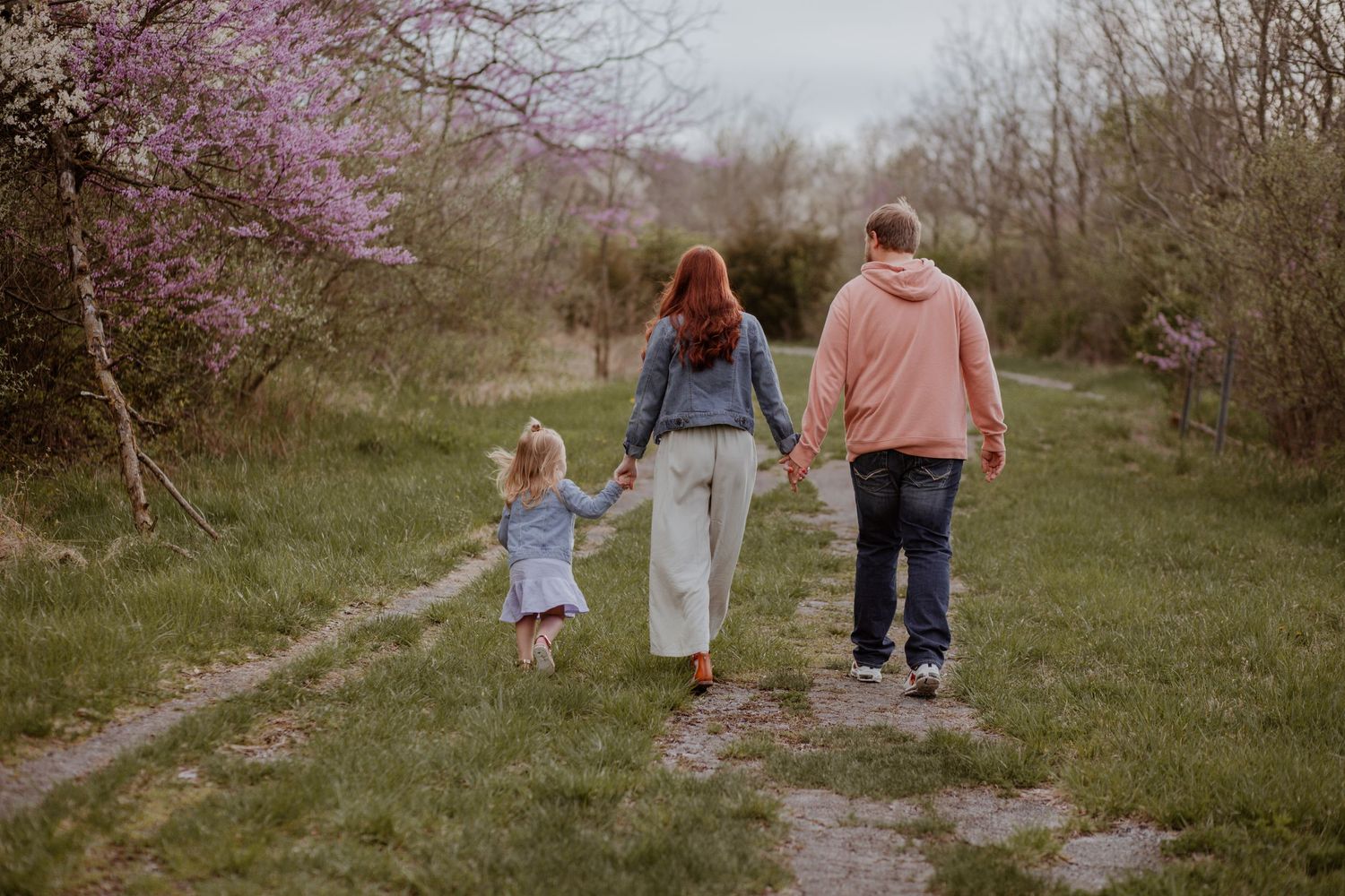 Family walking together on path surrounded by spring blossoms.