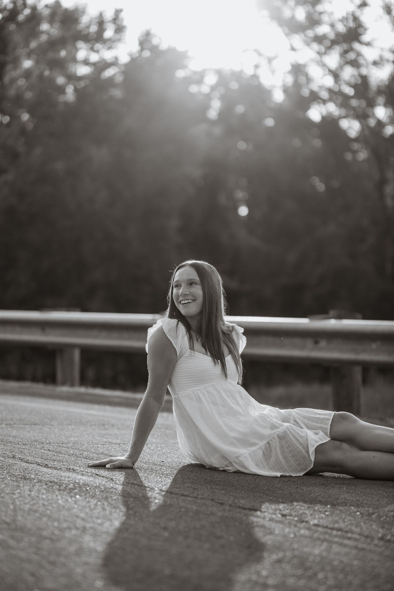 Black and white portrait of someone reclining on concrete during an outdoor photoshoot.