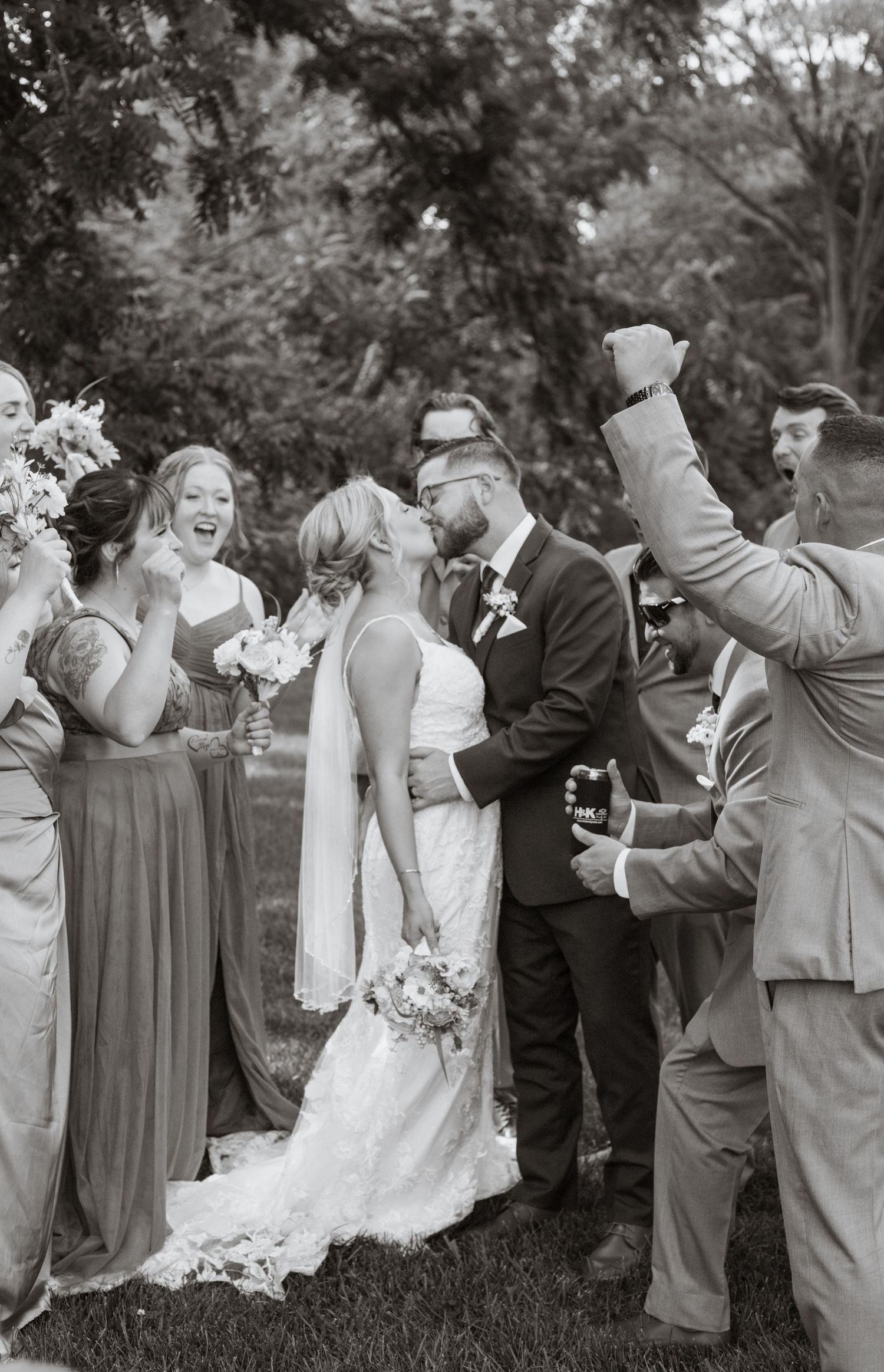 Wedding party celebrating with joyful reactions in a garden setting.