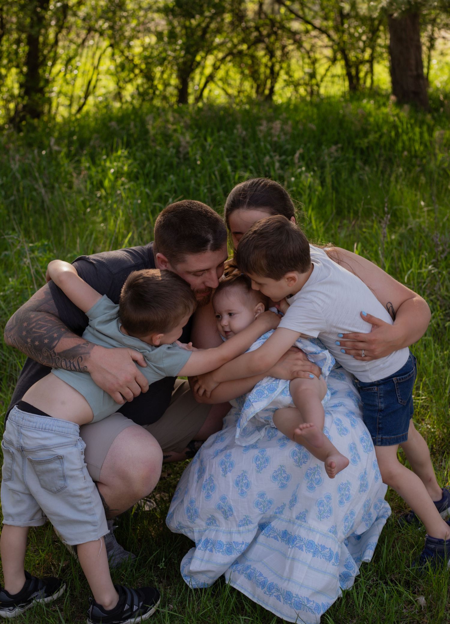 Candid family photos showing playful group hugs in lush green outdoor setting.
