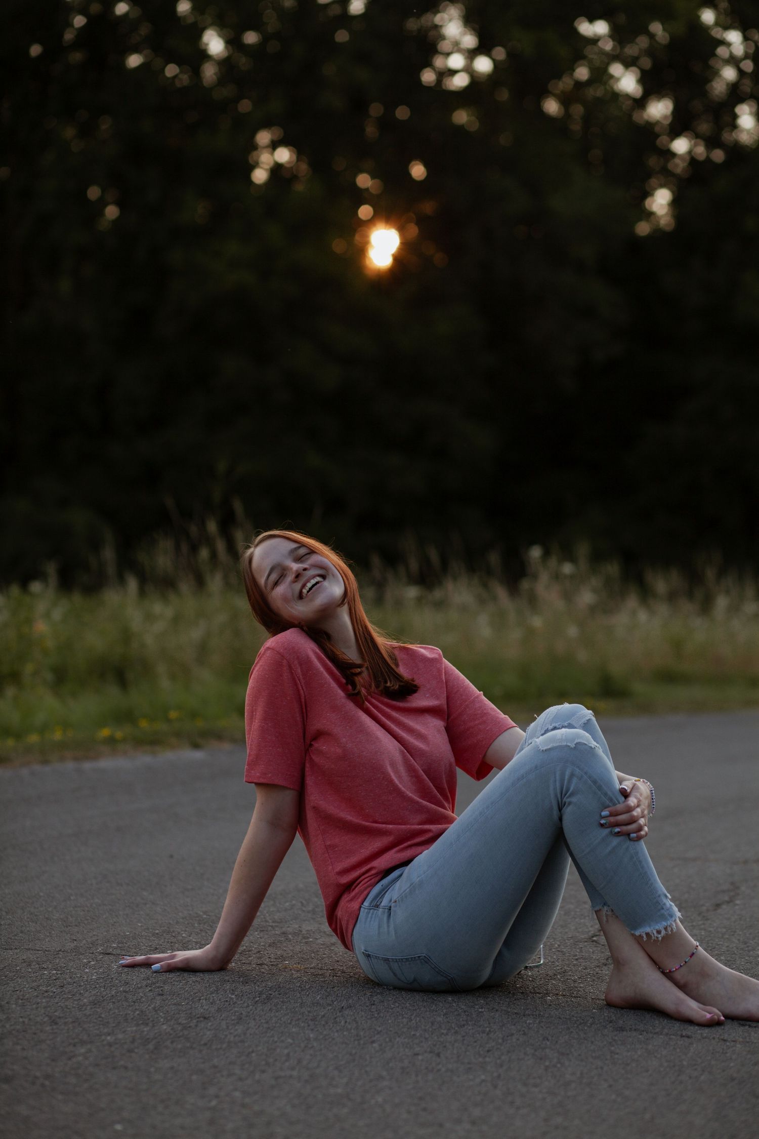 Casual sunset portrait session showing someone in jeans and coral shirt relaxing on pavement.