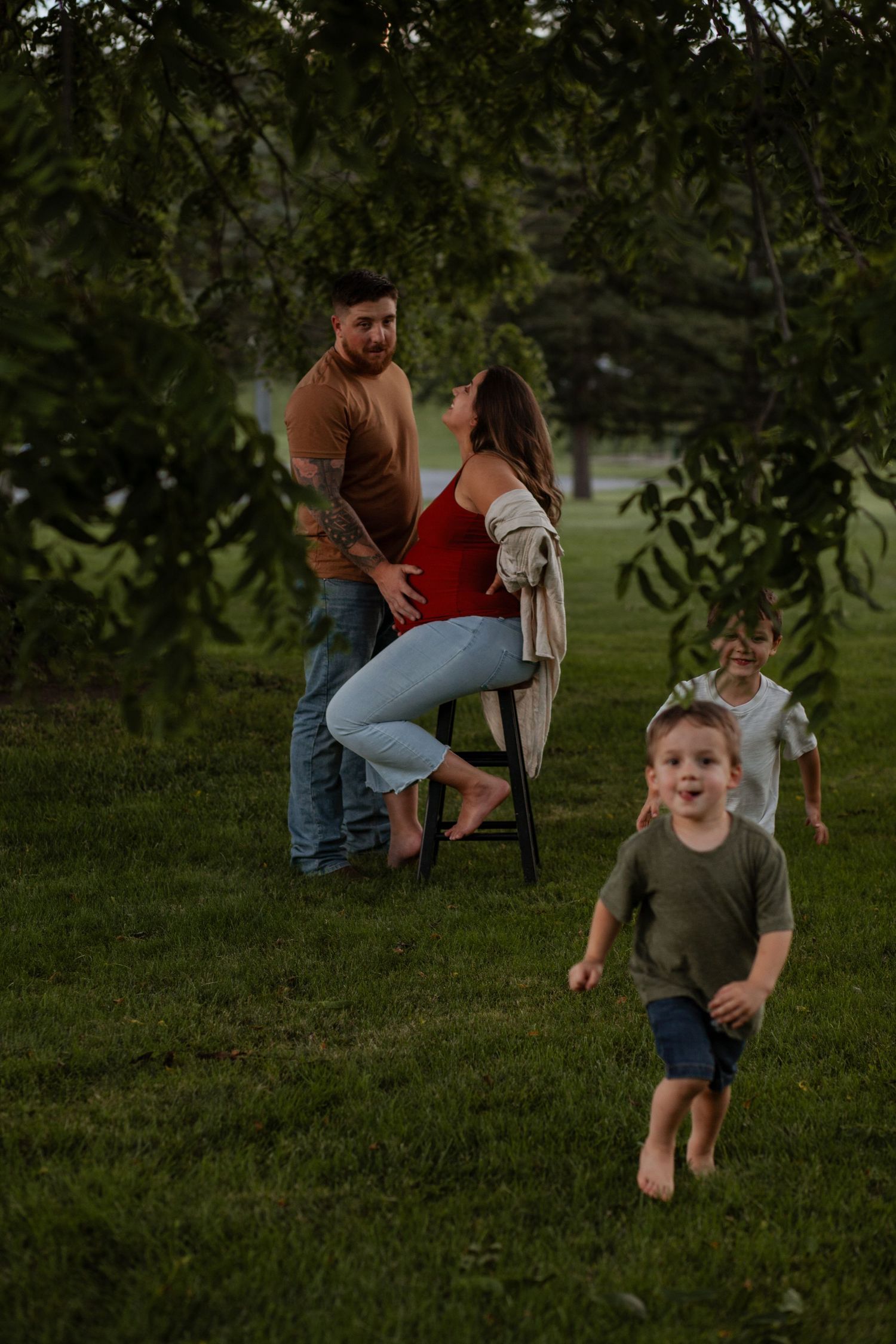 Playful family moment captured in a green park setting at dusk.
