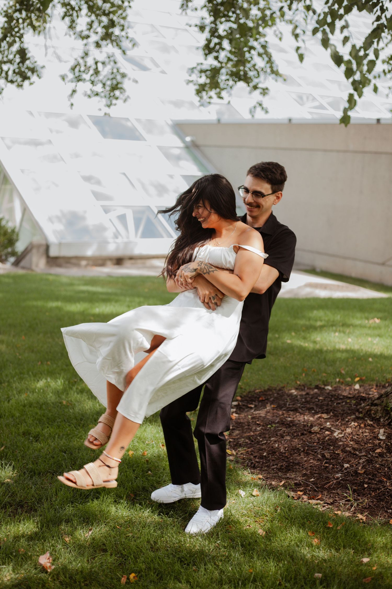 Romantic dip pose in garden with couple in white dress and black outfit.