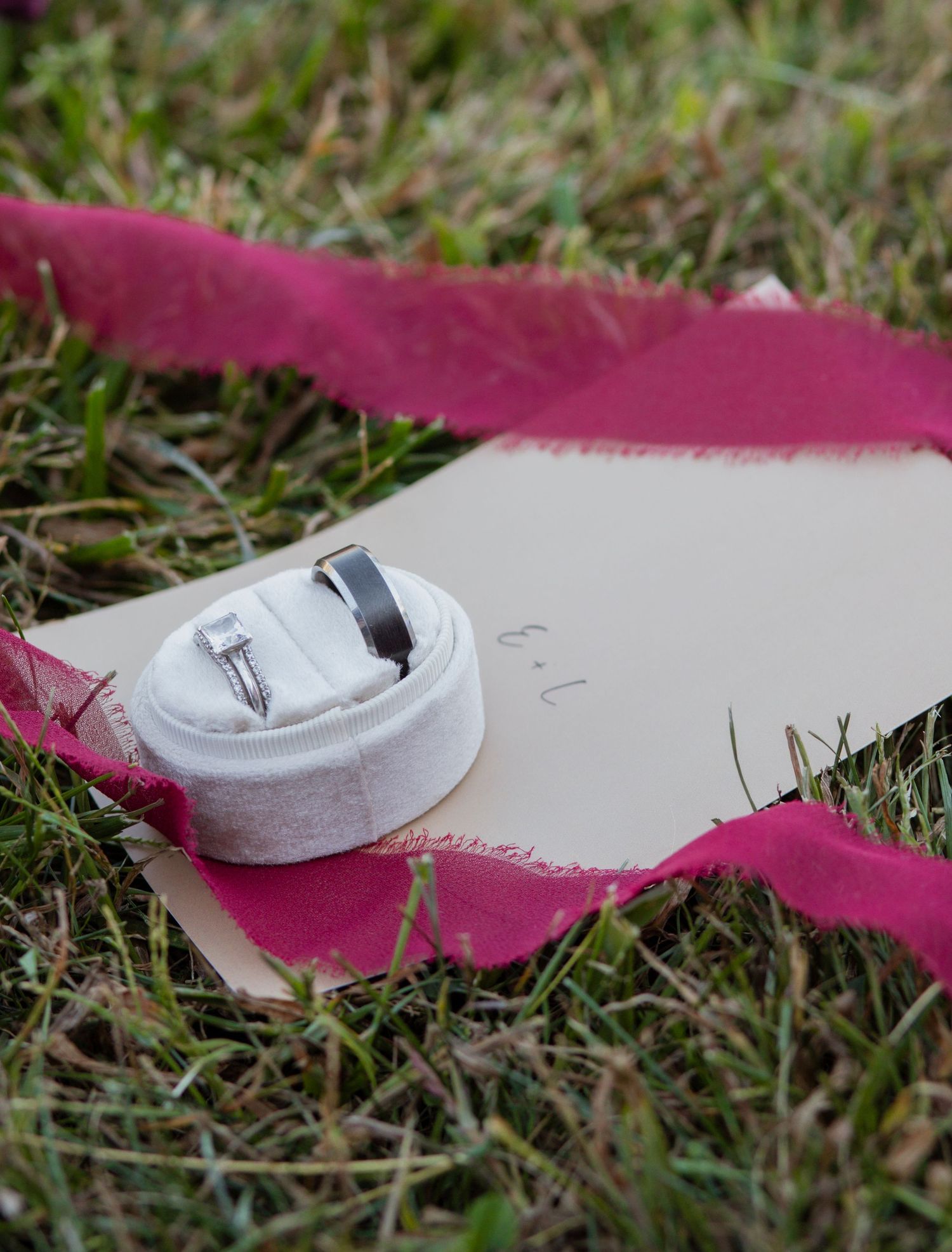 Close-up of white shoes with magenta fabric accents on grass.