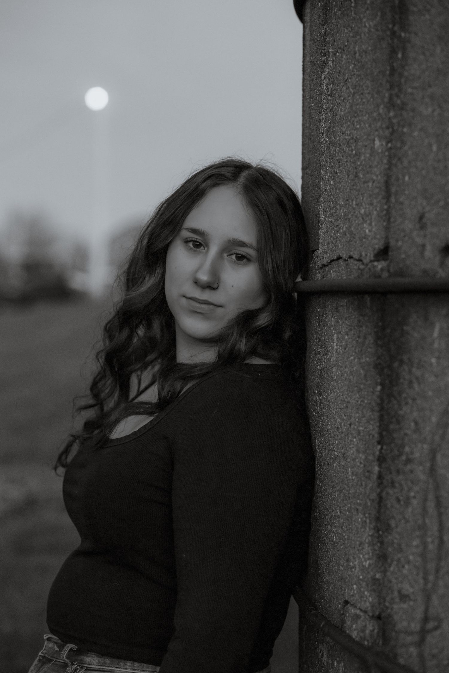 Moody black and white portraits taken against concrete pillars with a full moon in the background.