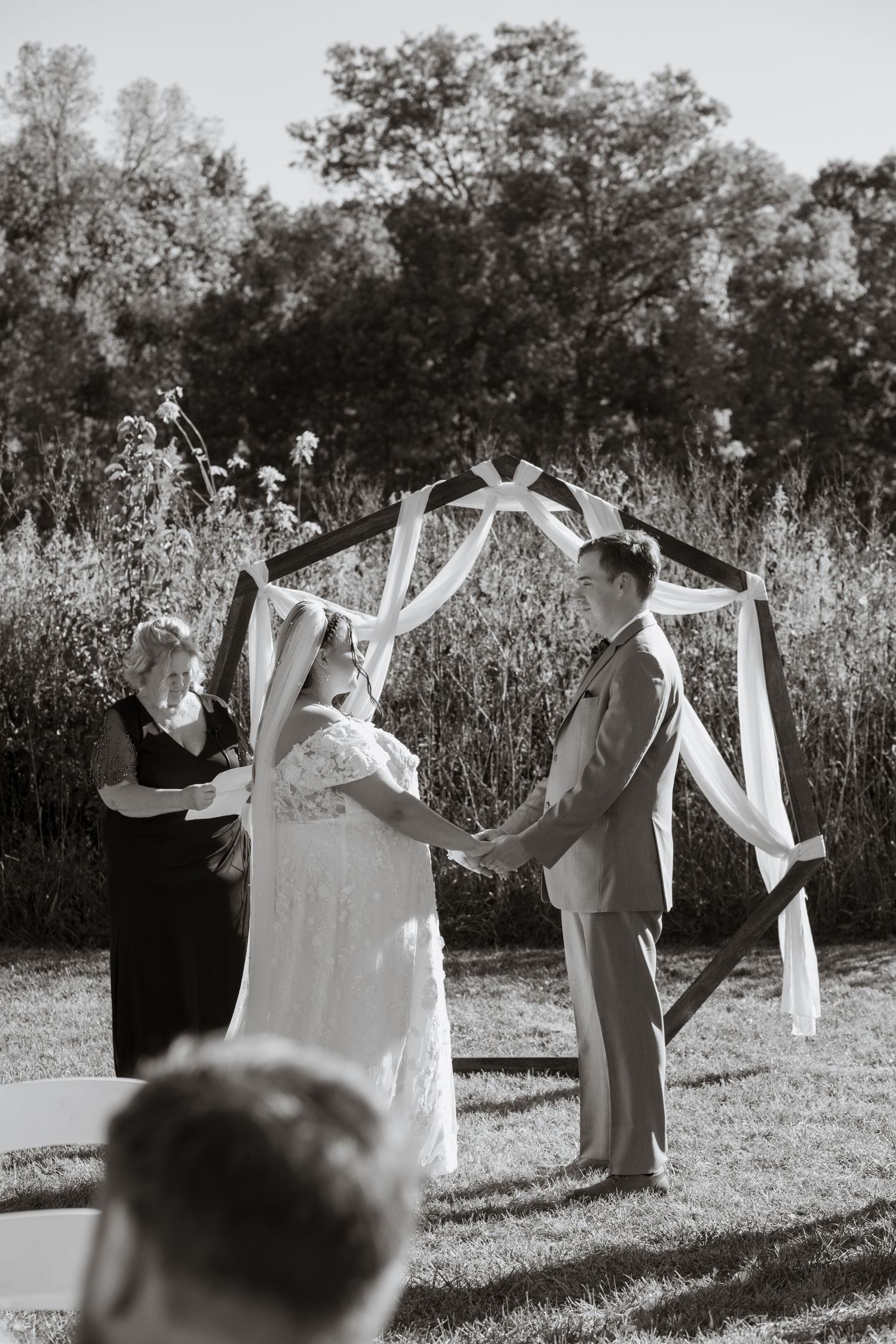 Black and white photo of wedding party holding garments on a clothesline outdoors.