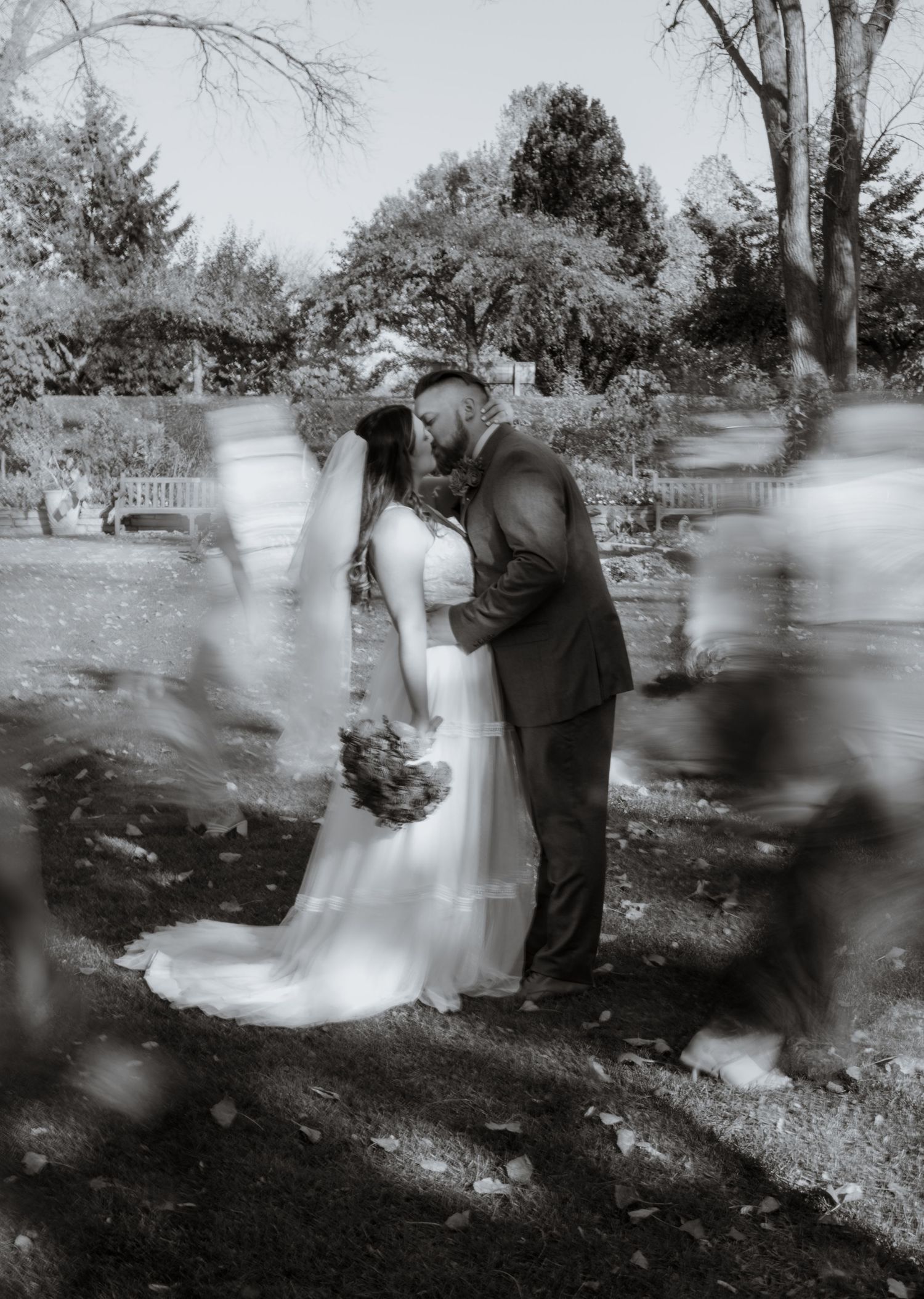 Black and white motion blur sequence of wedding couple in outdoor garden setting.