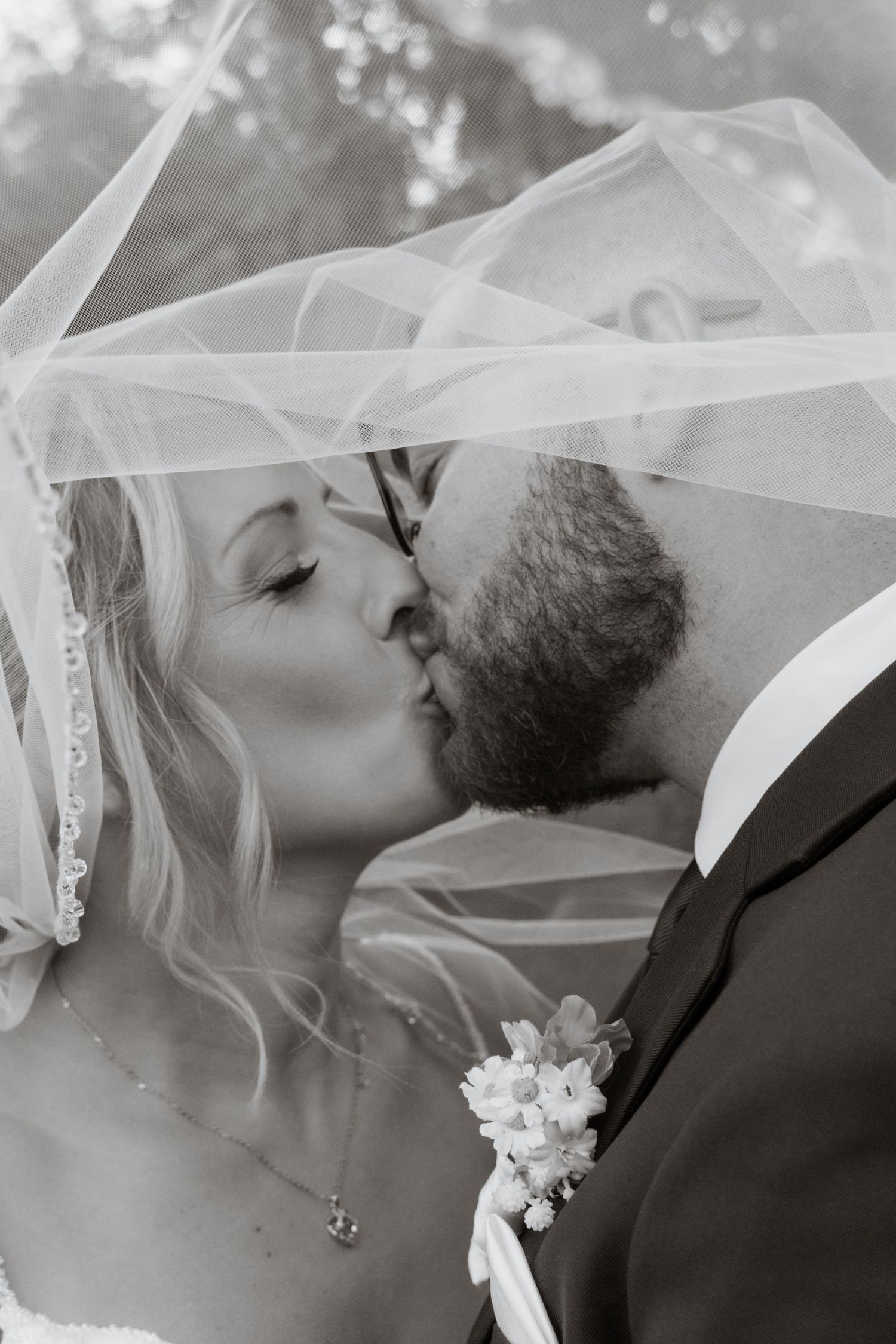 Black and white wedding photo series showing intimate moments under a flowing veil.