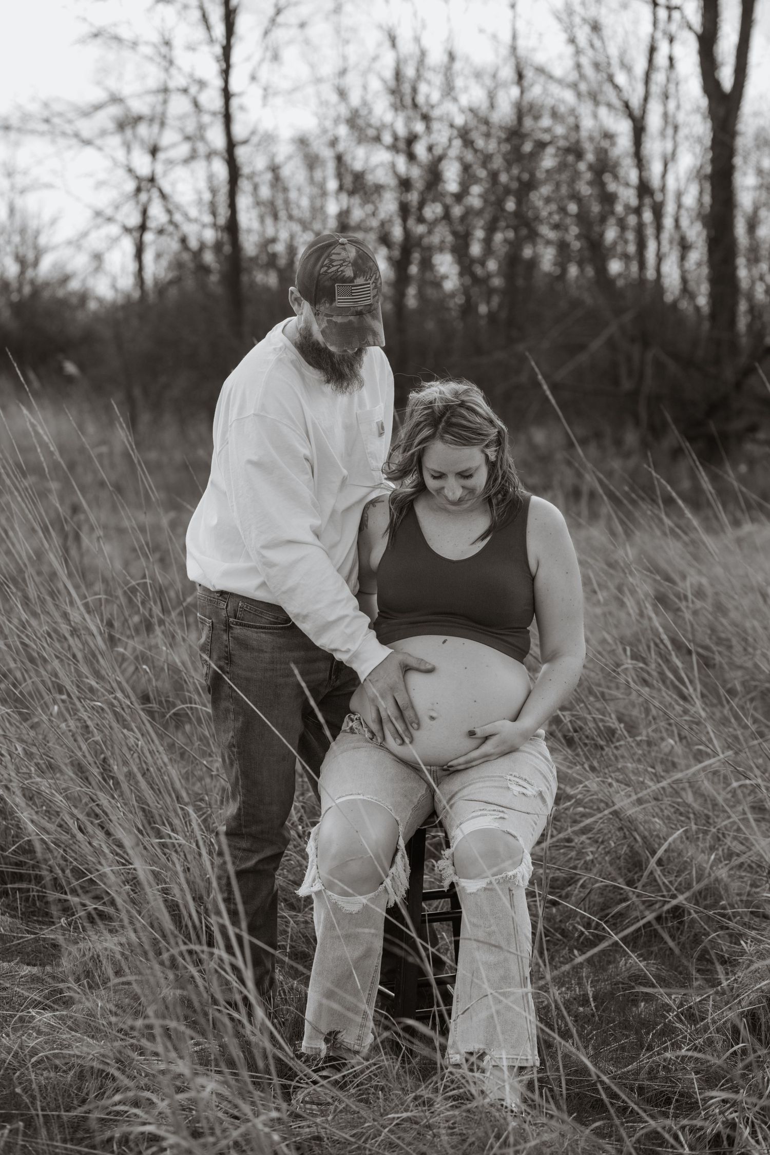 Artistic black and white maternity photo shoot in a field of tall grass.