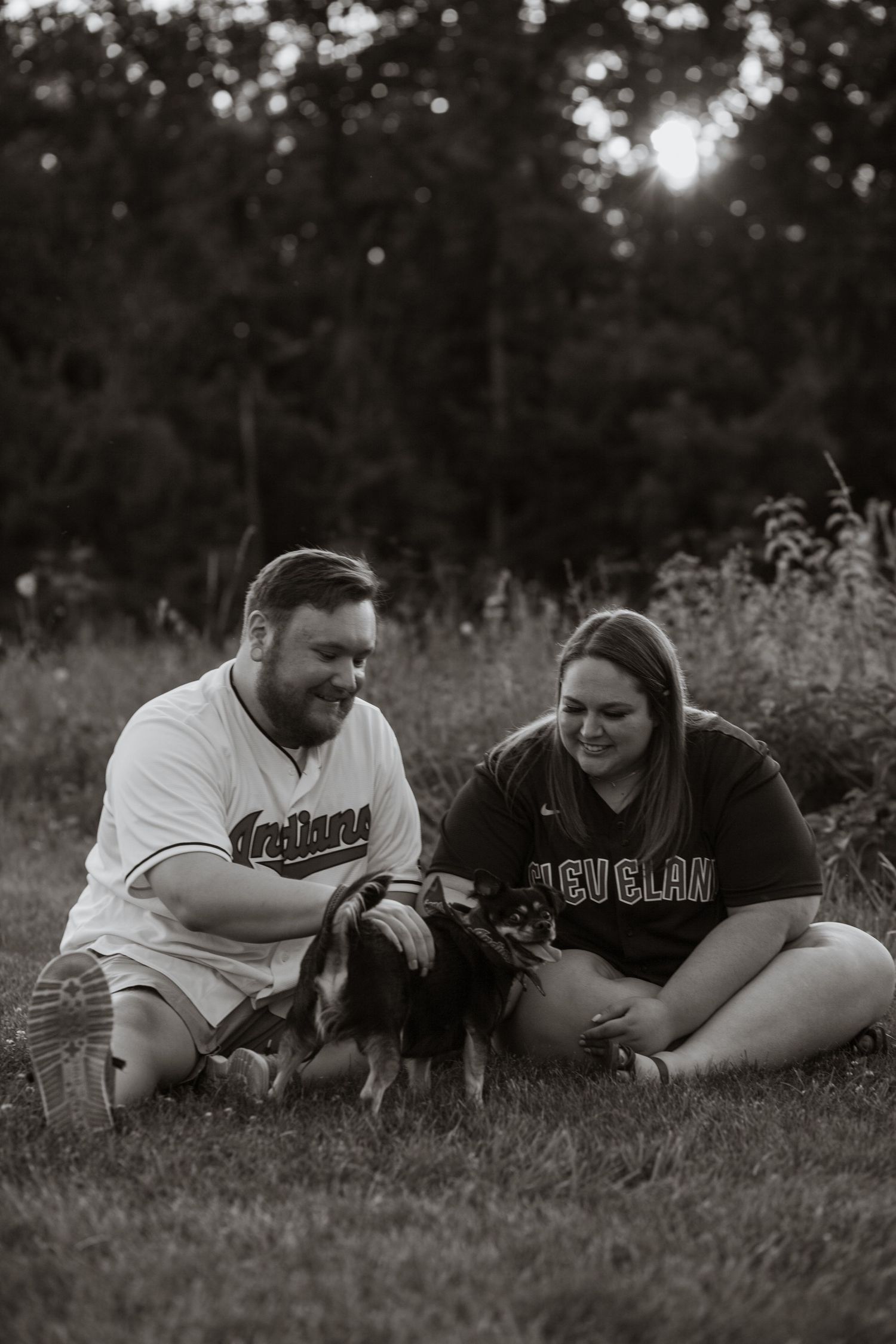 Couple lying in grass at sunset with playful expressions.