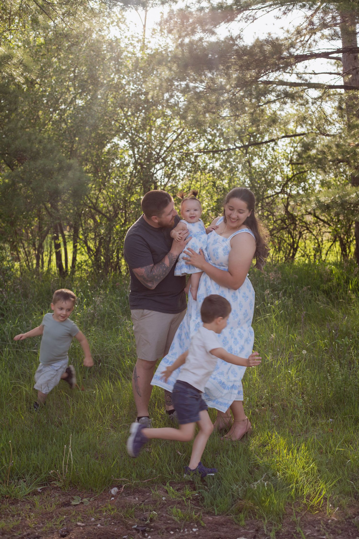 Family playing and running together in a sunlit field during golden hour.