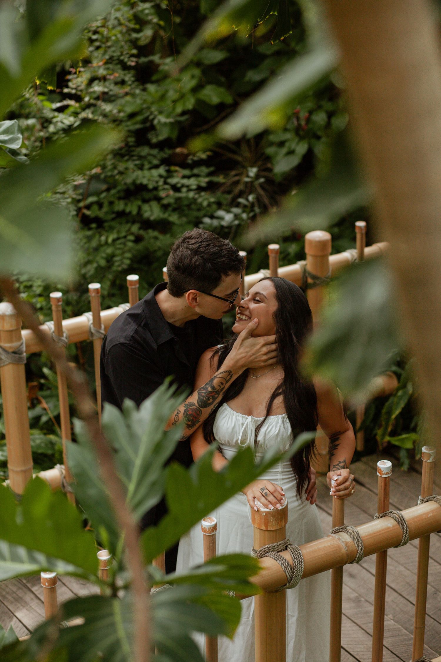 Intimate moment captured between couple near bamboo fence.
